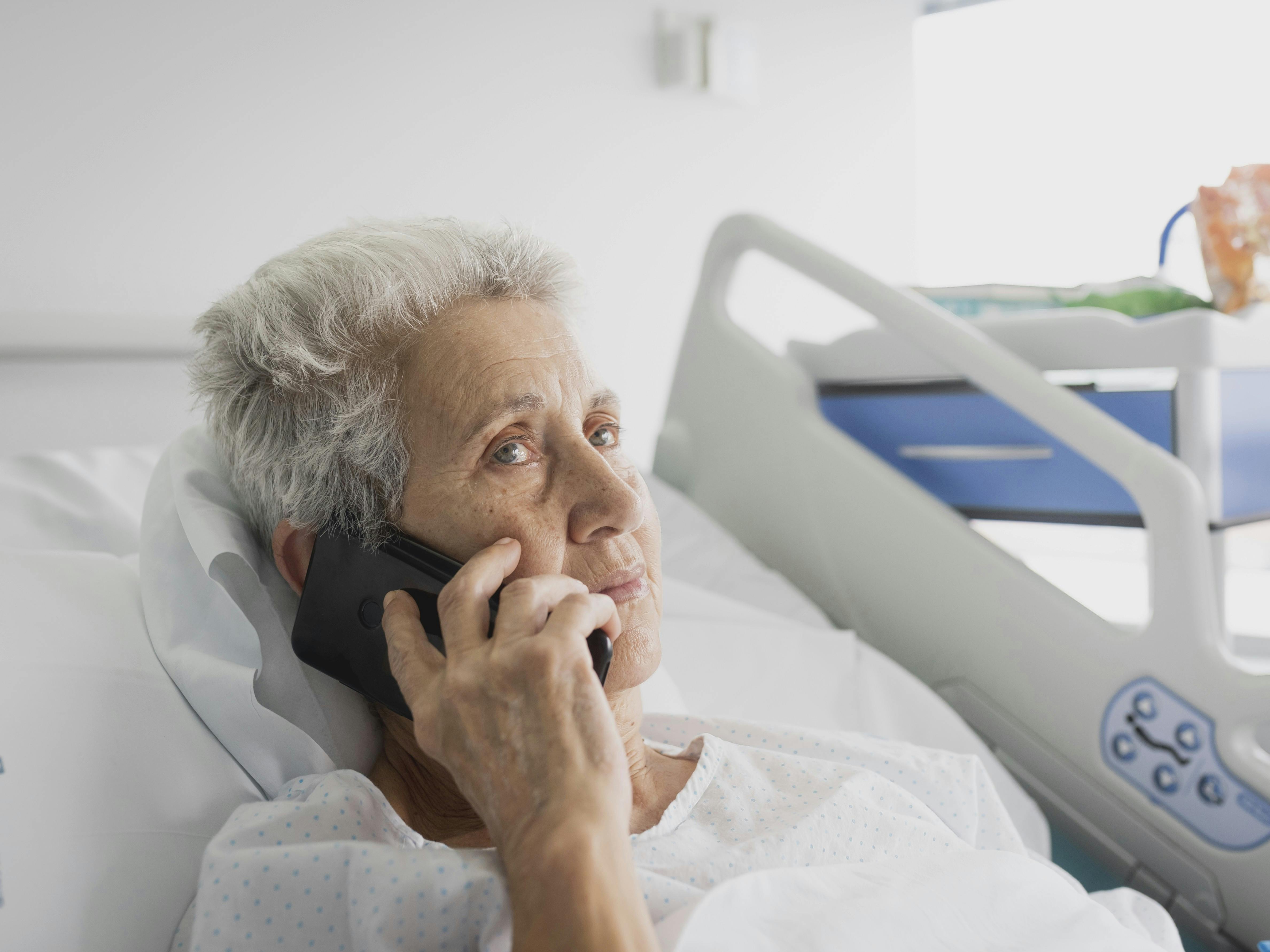 sick hospitalized elderly woman talking on the phone