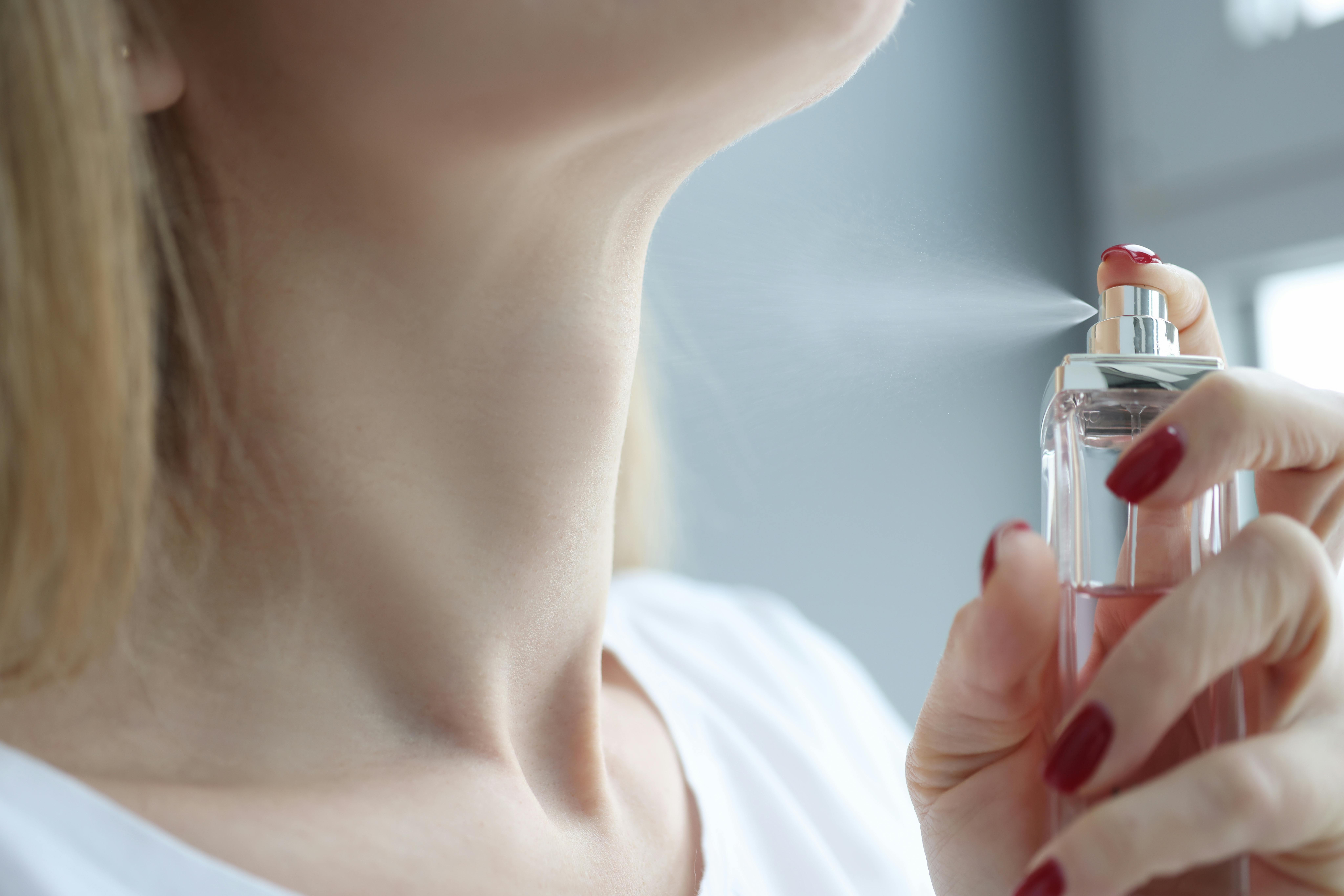 Kvinde sprøjter parfume på sin hals
