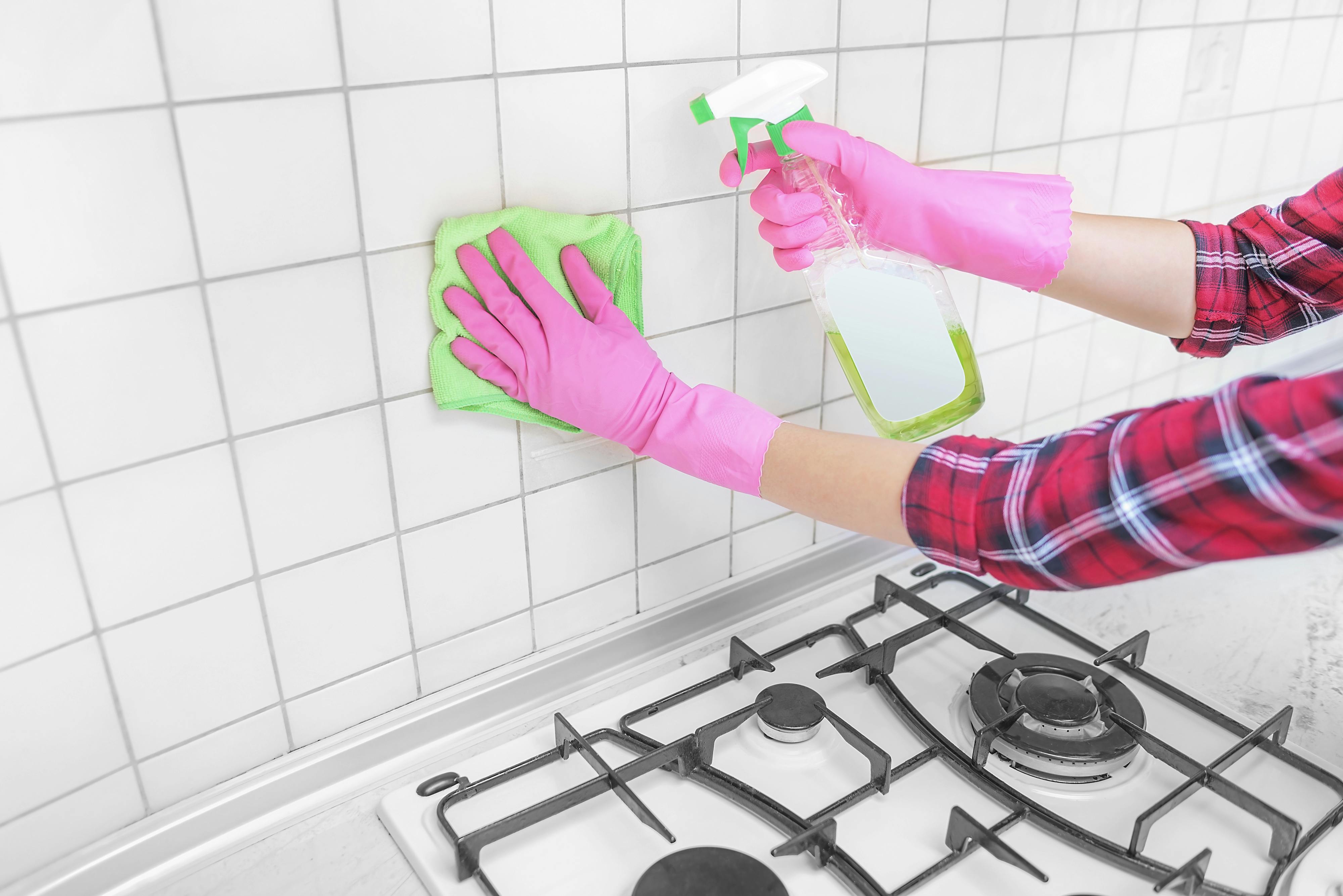 Female hands in gloves wash their the tile in the kitchen.