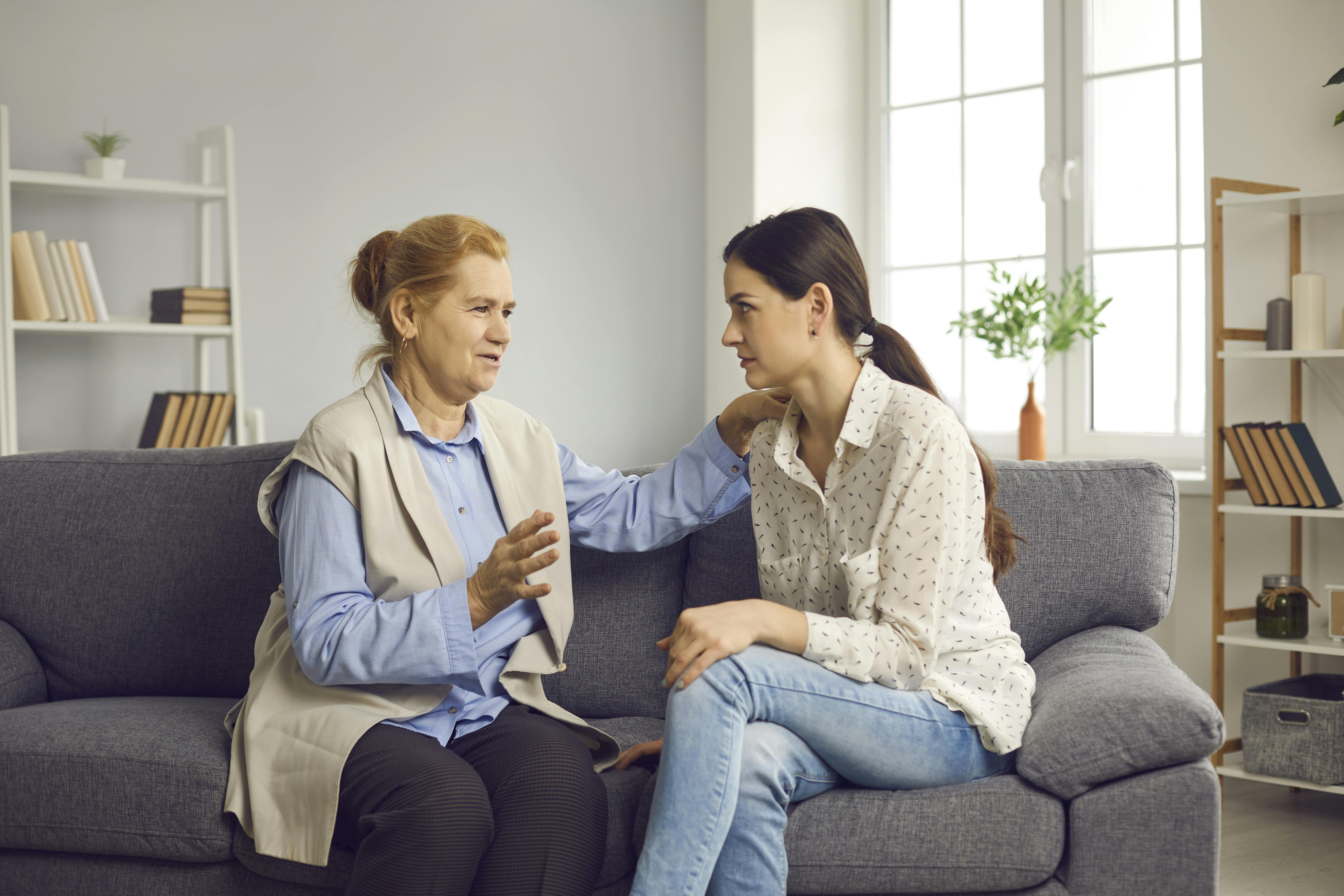 Svigermor og svigerdatter sidder over for hinanden i en sofa og taler alvorligt sammen.