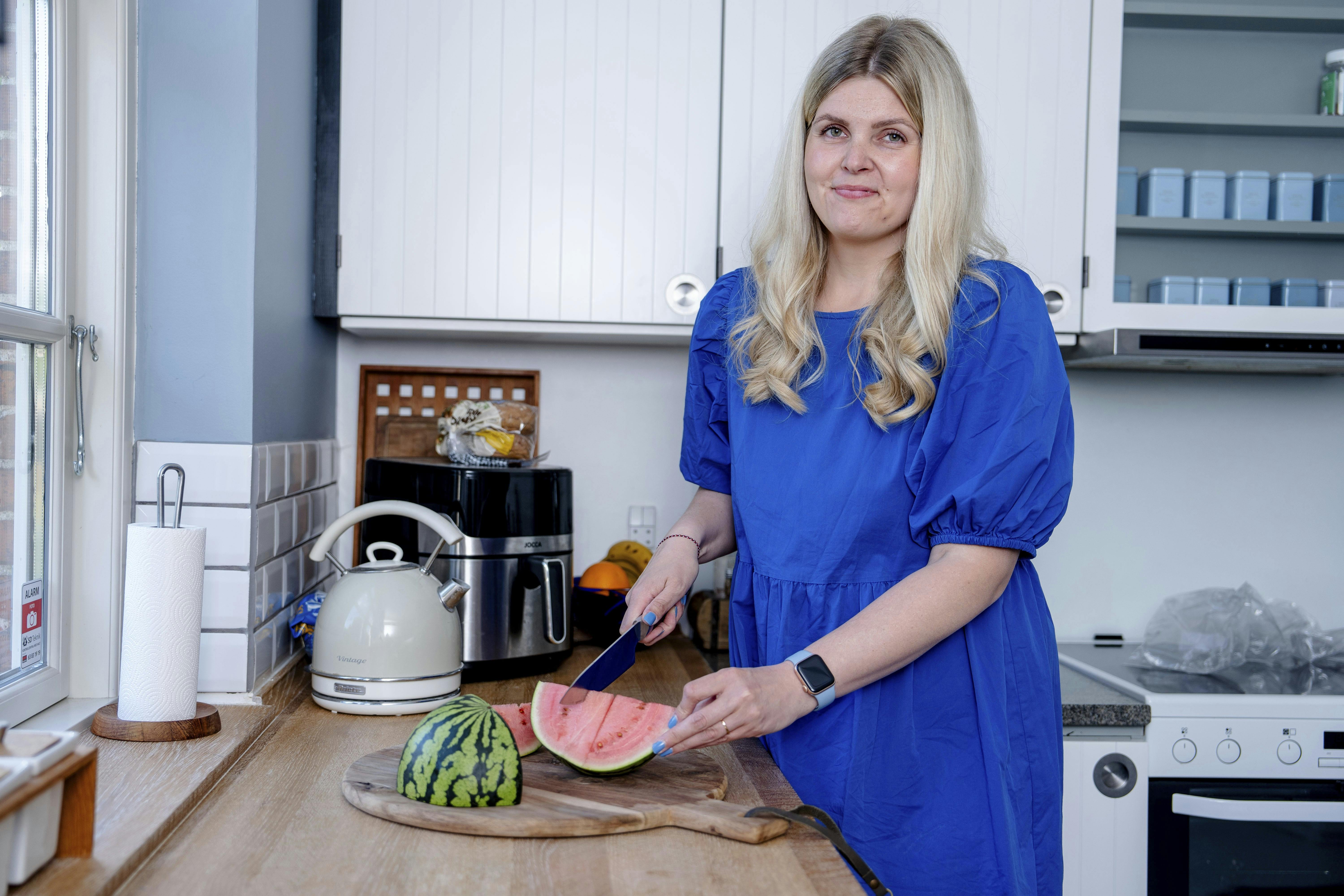 Louise Lorensen i sit køkken i gang med at skære en vandmelon i både.