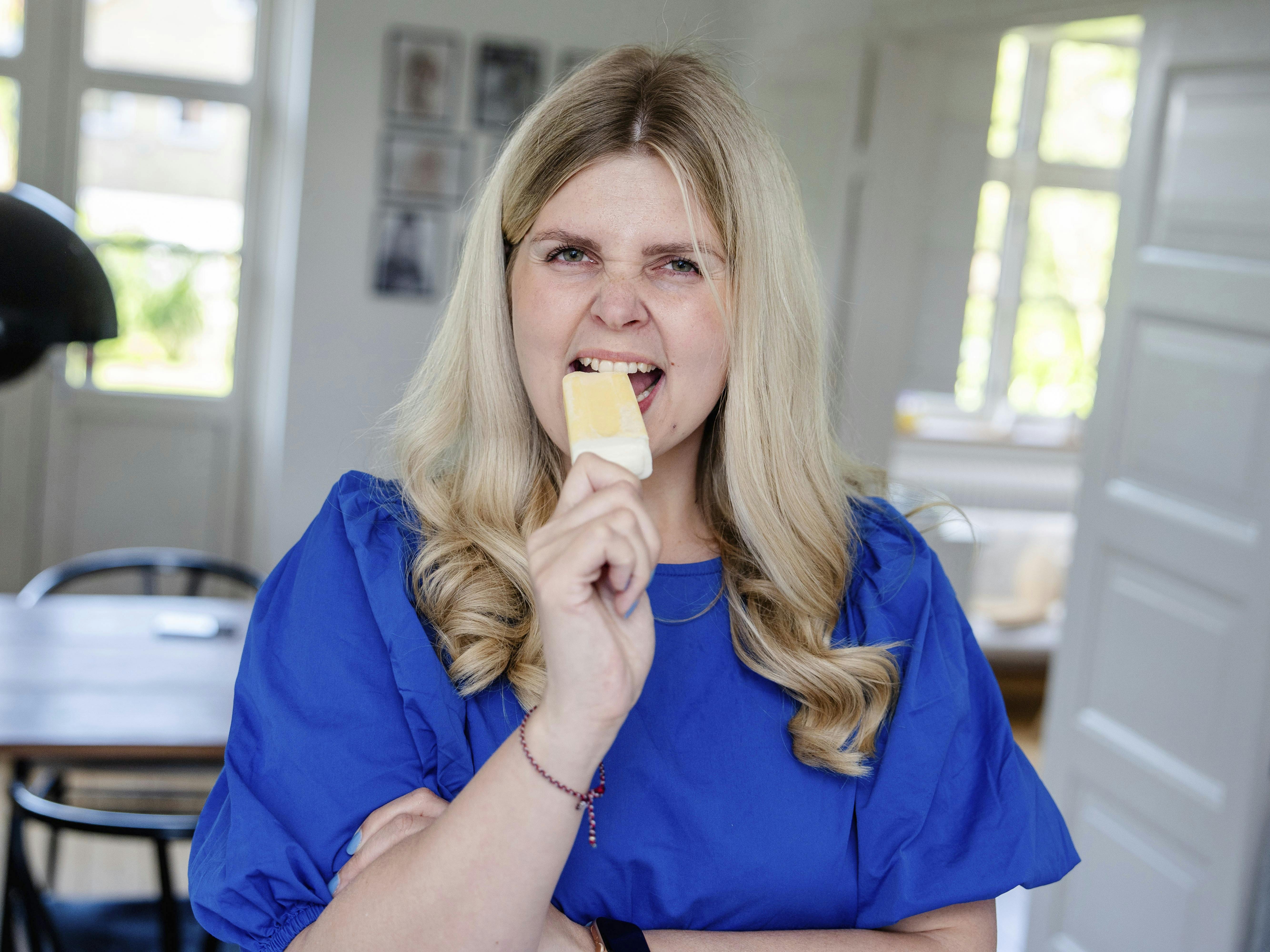 Louise Lorensen står i sit hjem I Hellerup og tager en bid af en ispind.