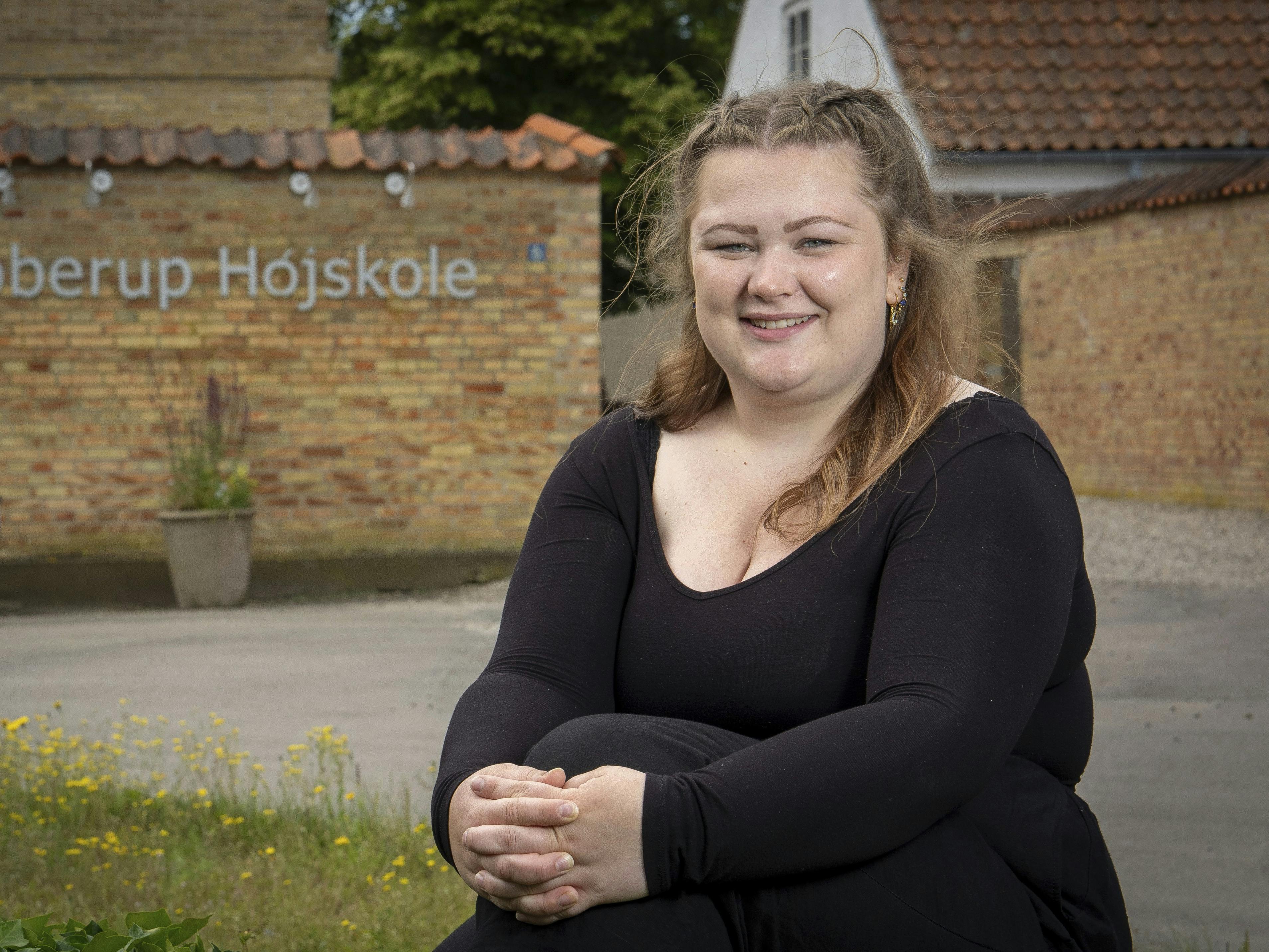 Pernille Høybye Jensen er på Ubberup Højskole. Her sidder hun på en stor sten foran højskolens bygning.