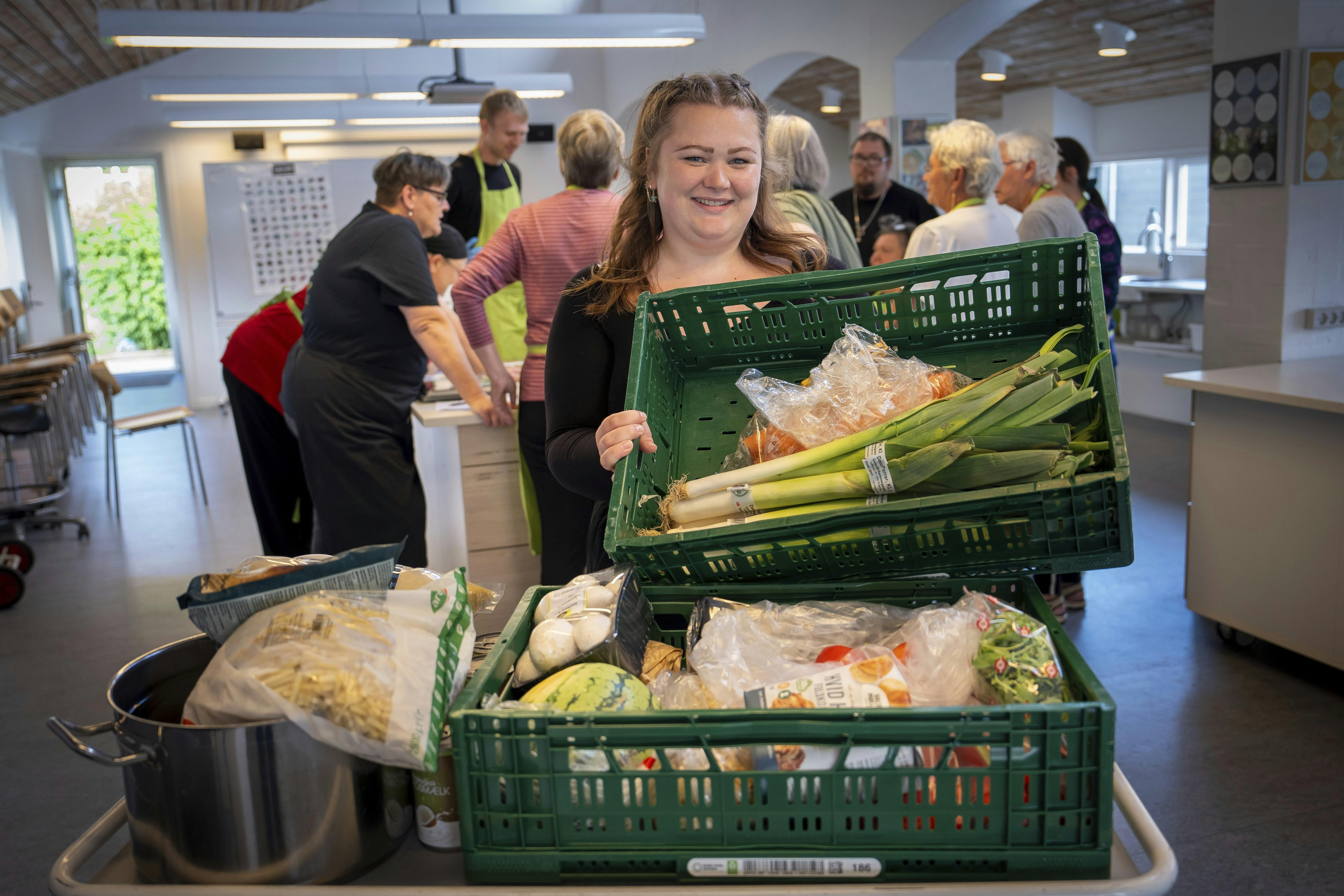 Pernille Høybye Jensen i køkkenet på Ubberup Højskole. Her står hun med en stor grøn kasse med grøntsager.