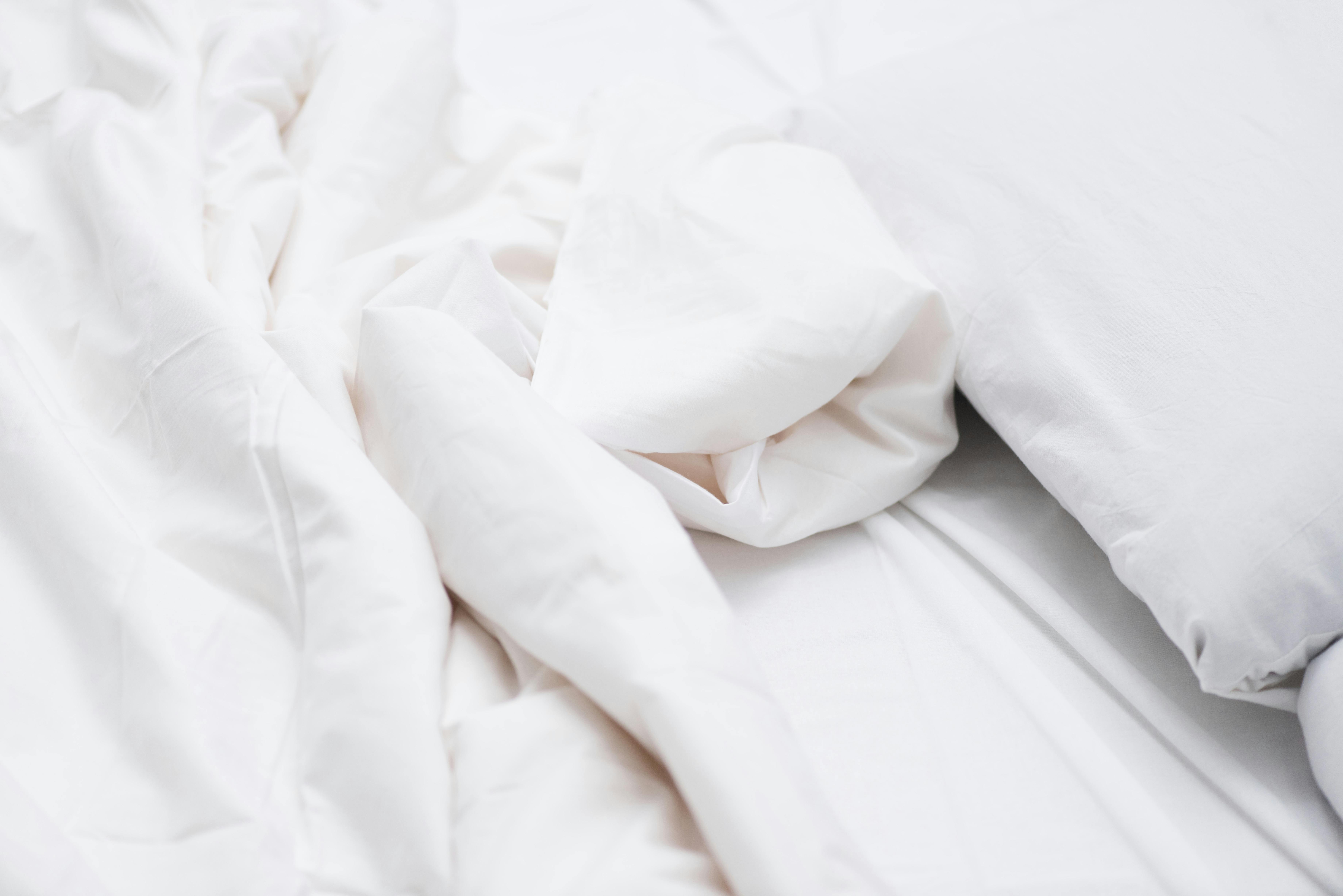 Close up of bed with white sheets and blanket 