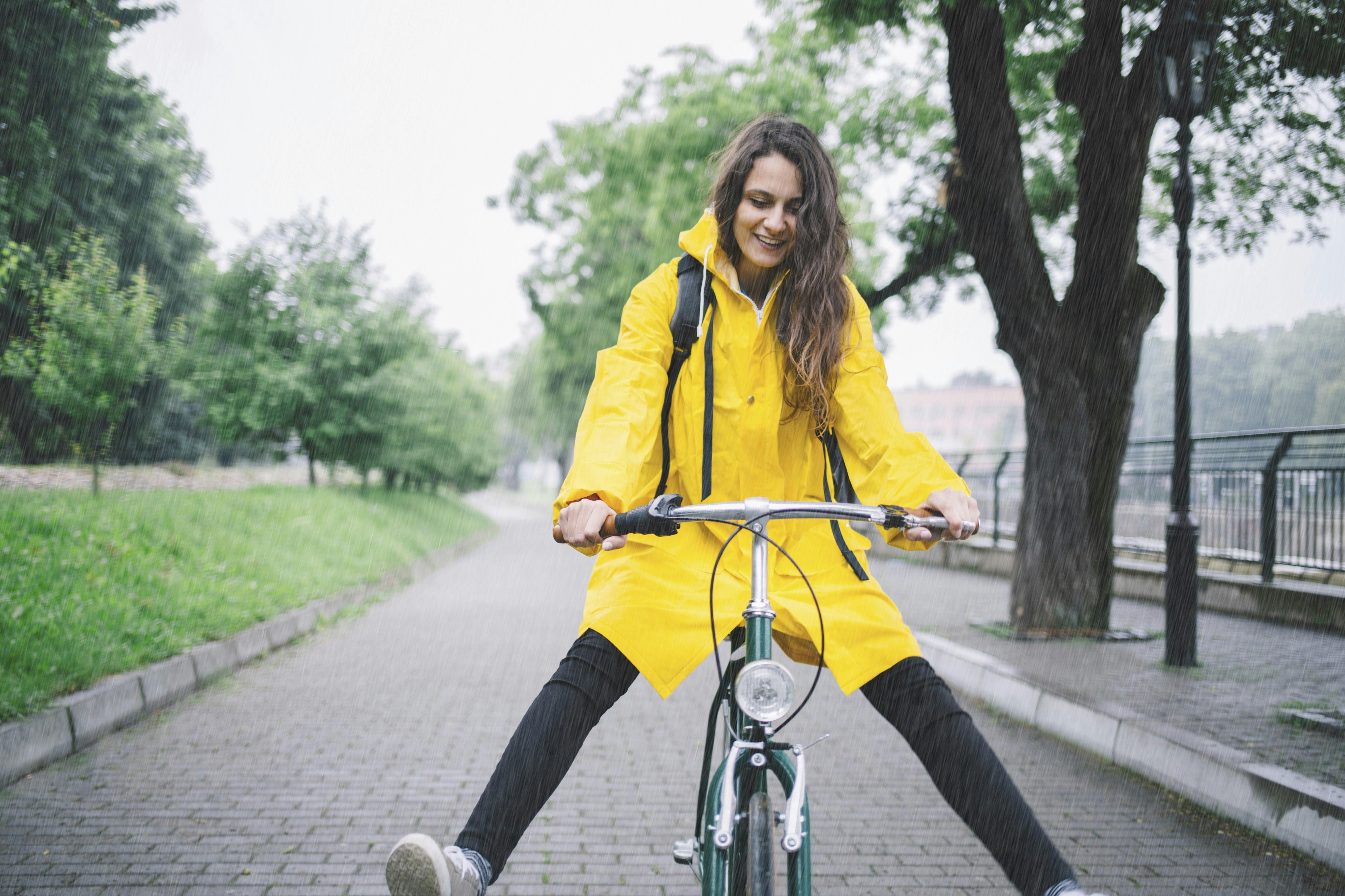 En kvinde der cykler, imens hun har regnjakke på. 