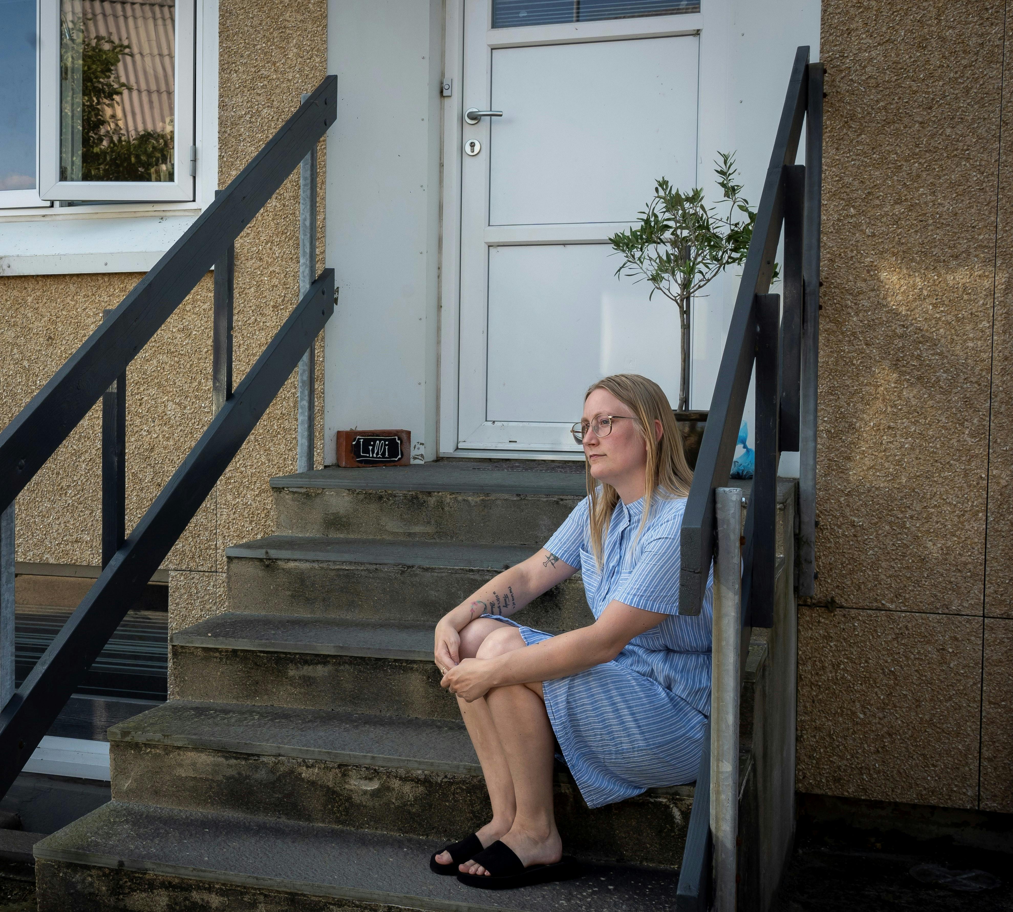 Cecilie sidder på trappen foran morens hjem.