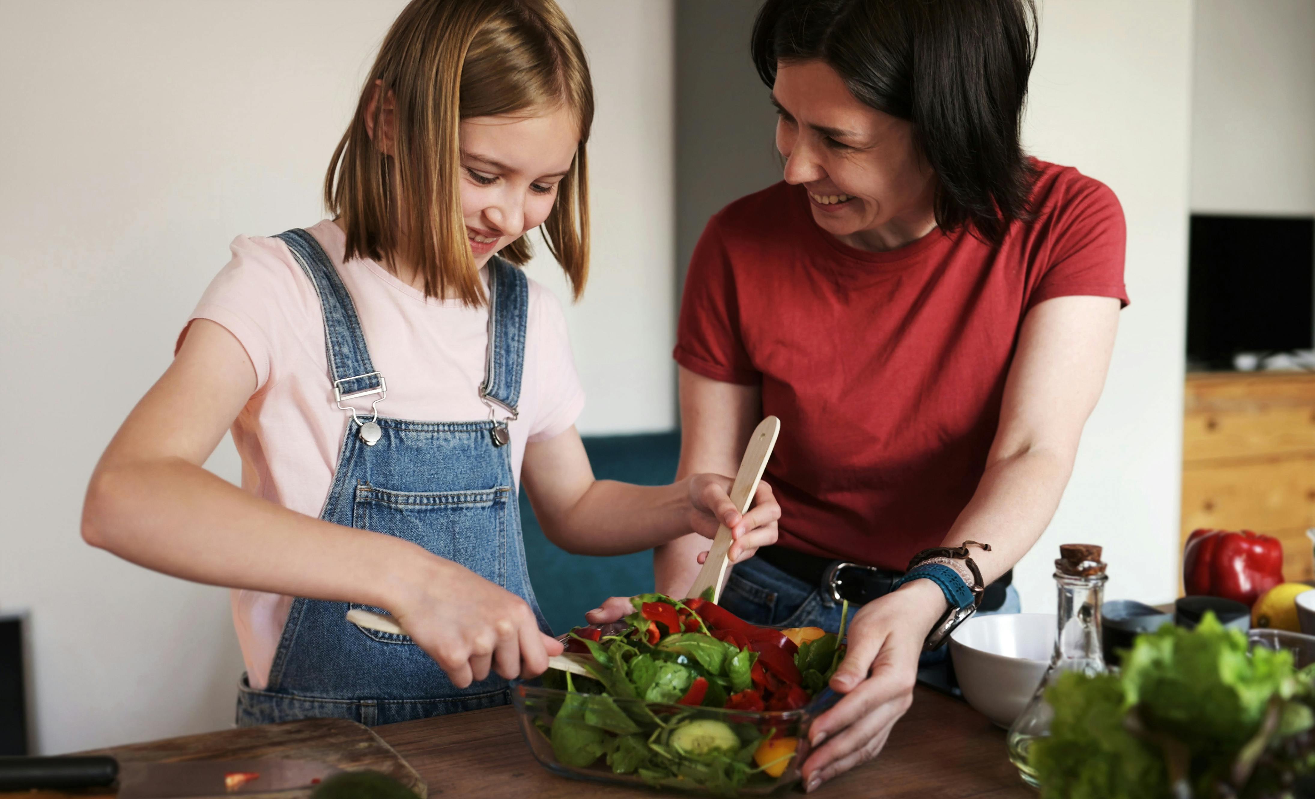 Mother Teaching Her Cute Beautiful Daughter To Cook A Vegetable Salad