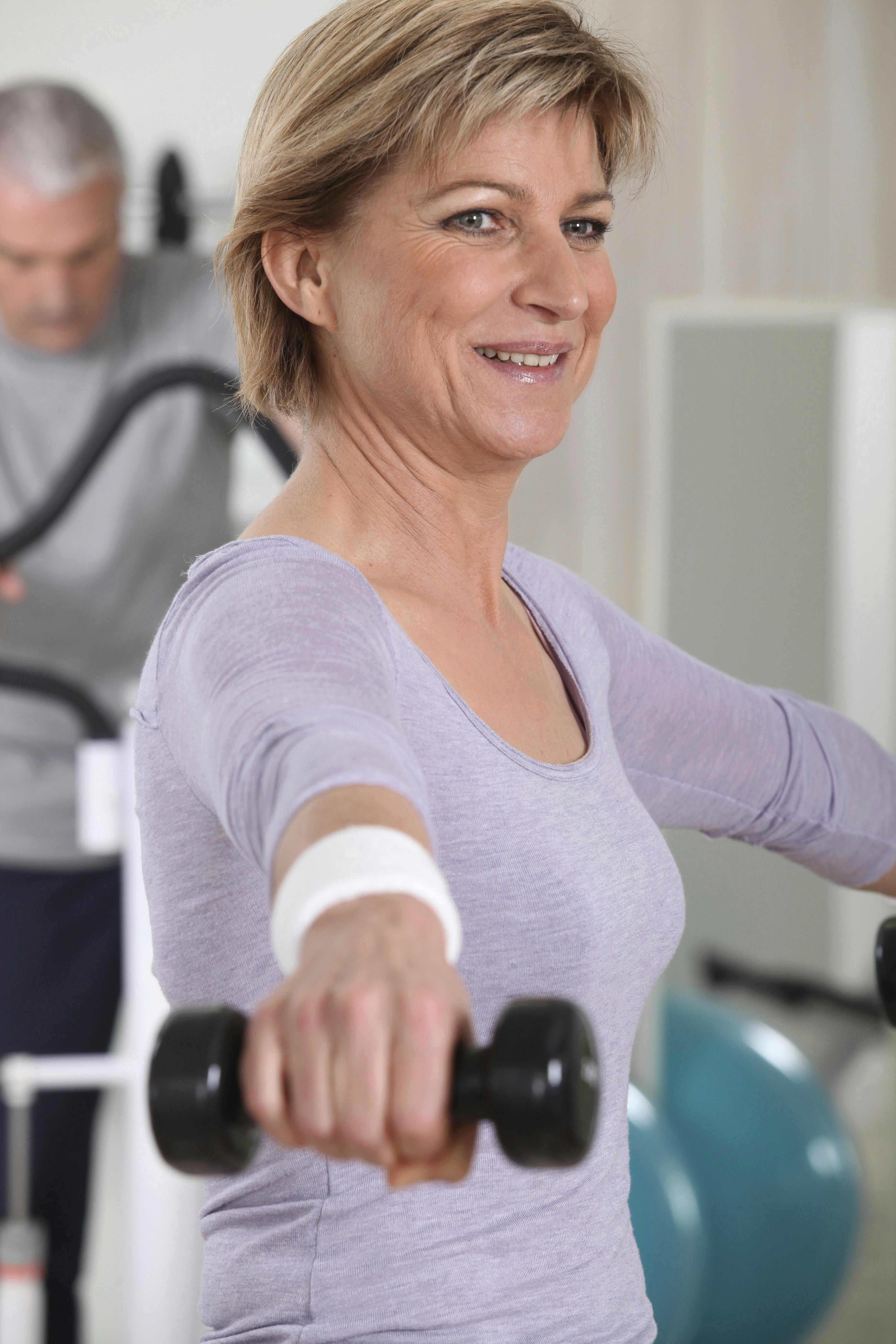 En kvinde der løfter håndvægte i fitness. 