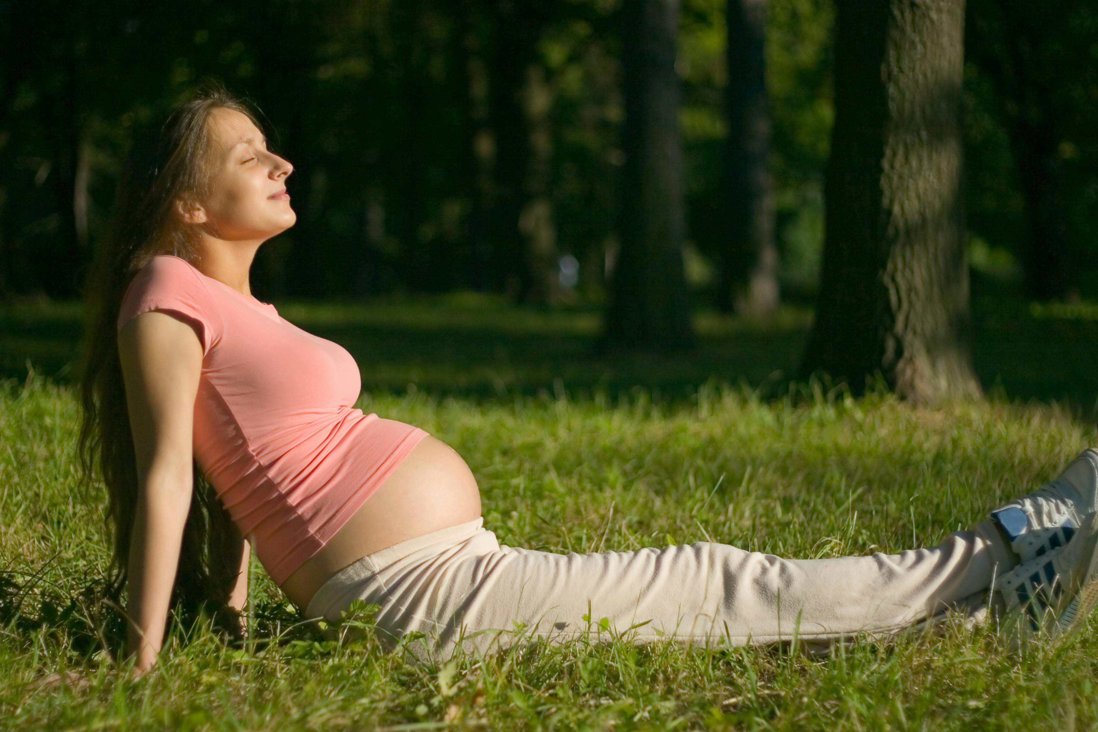 Ung gravid kvinde smiler i solen