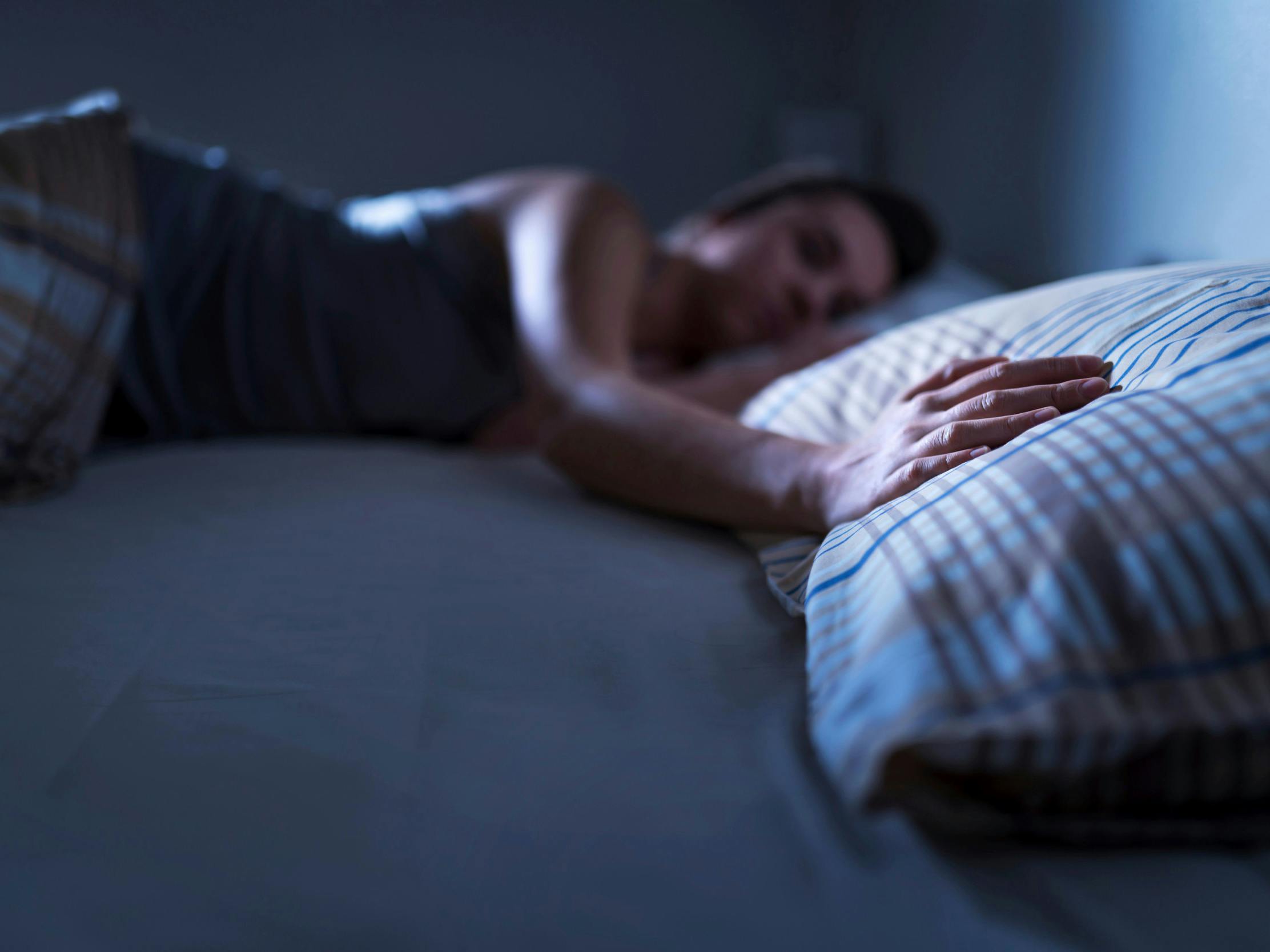 Sovende kvinde lægger hånden på den tomme pude ved hendes side.