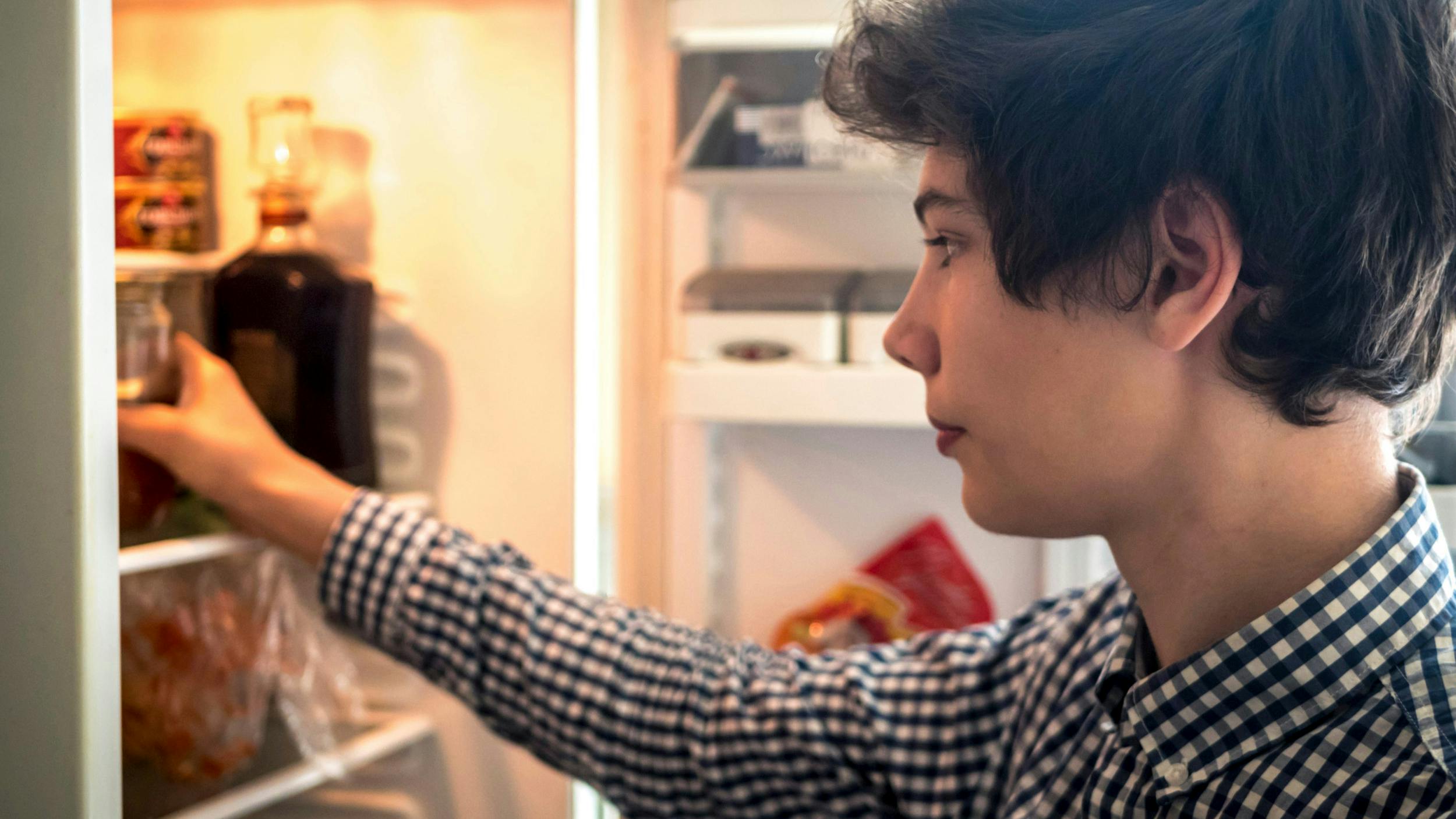 Teenagedreng leder efter mad i køleskabet.
