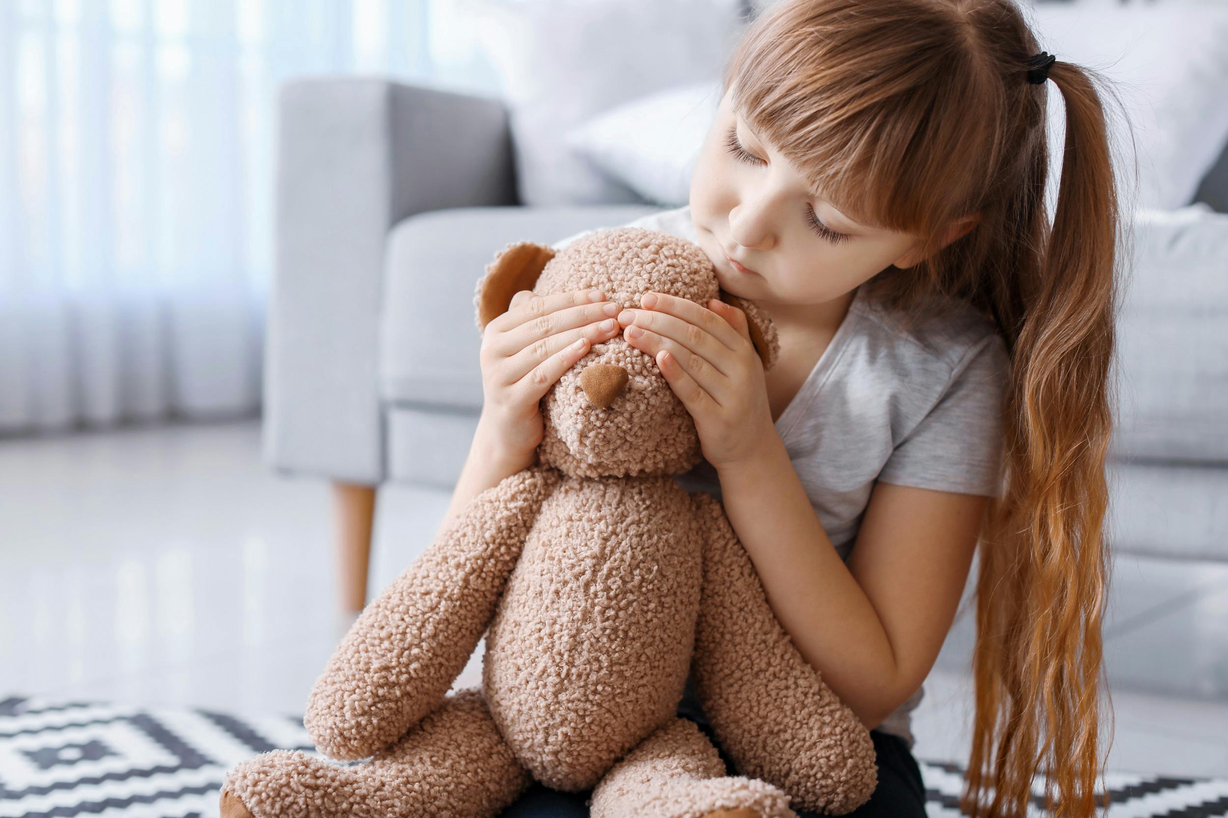 Trist, lille pige holder sin bamse for øjnene. 
