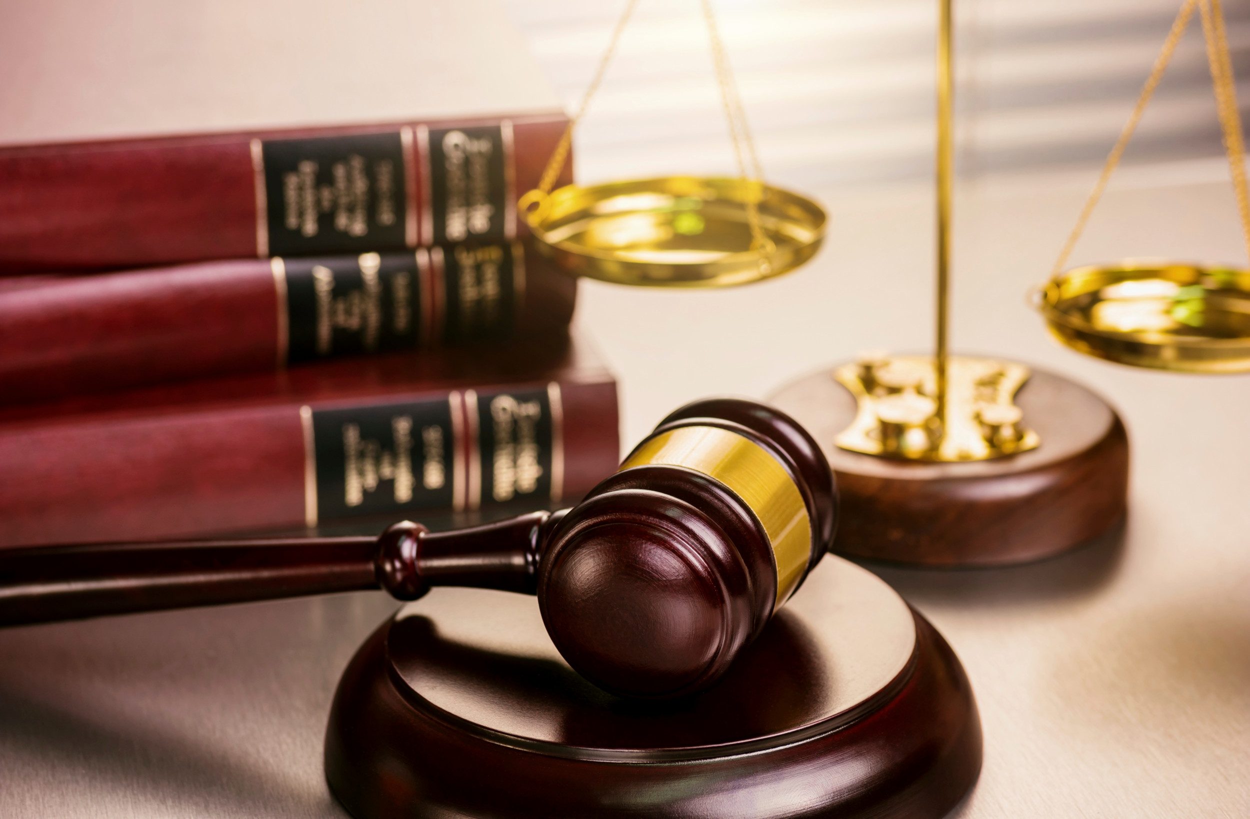 Opstilling med tre lovbøger, en vægt og en dommers hammer