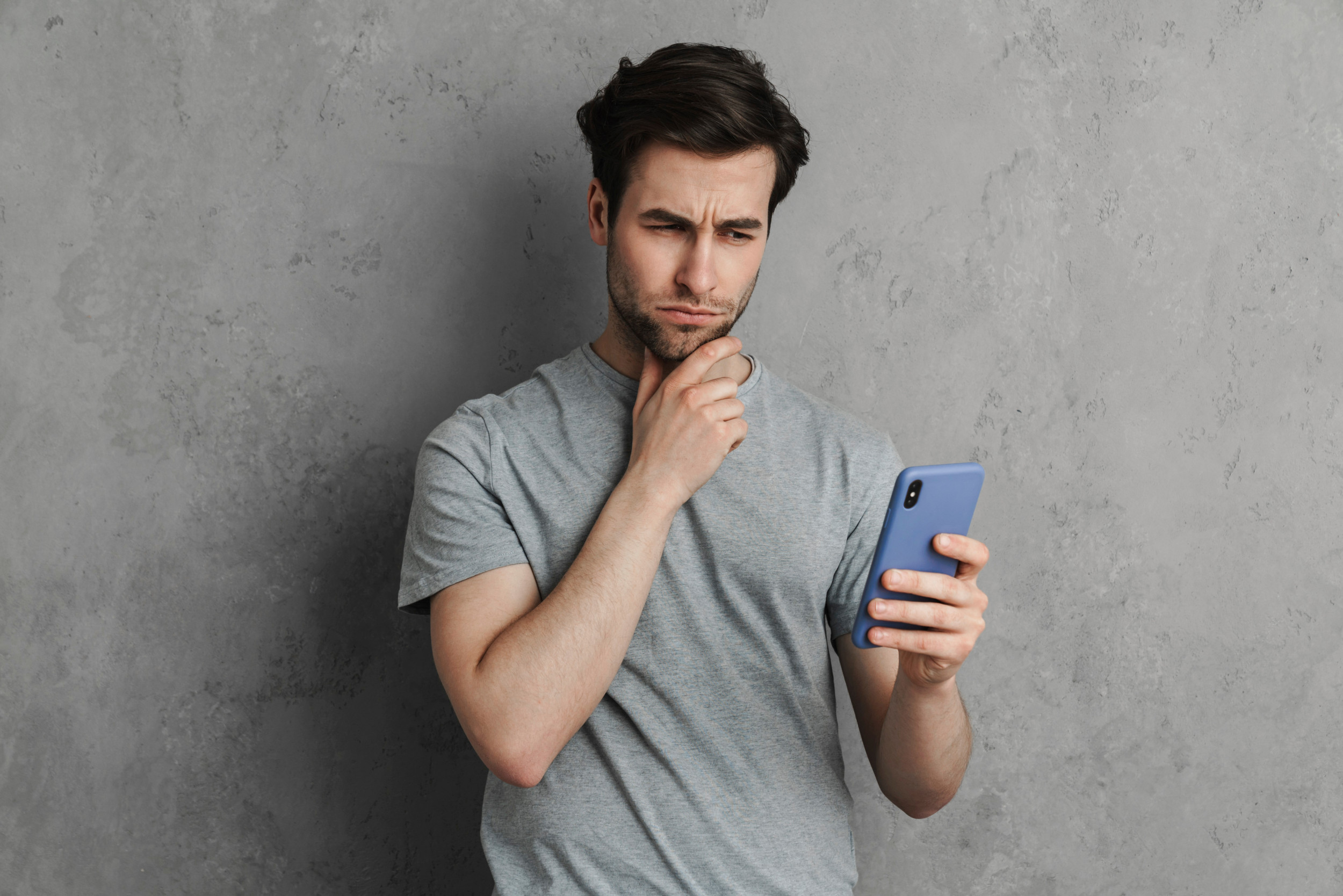Yngre mand ser skeptisk på en mobil.