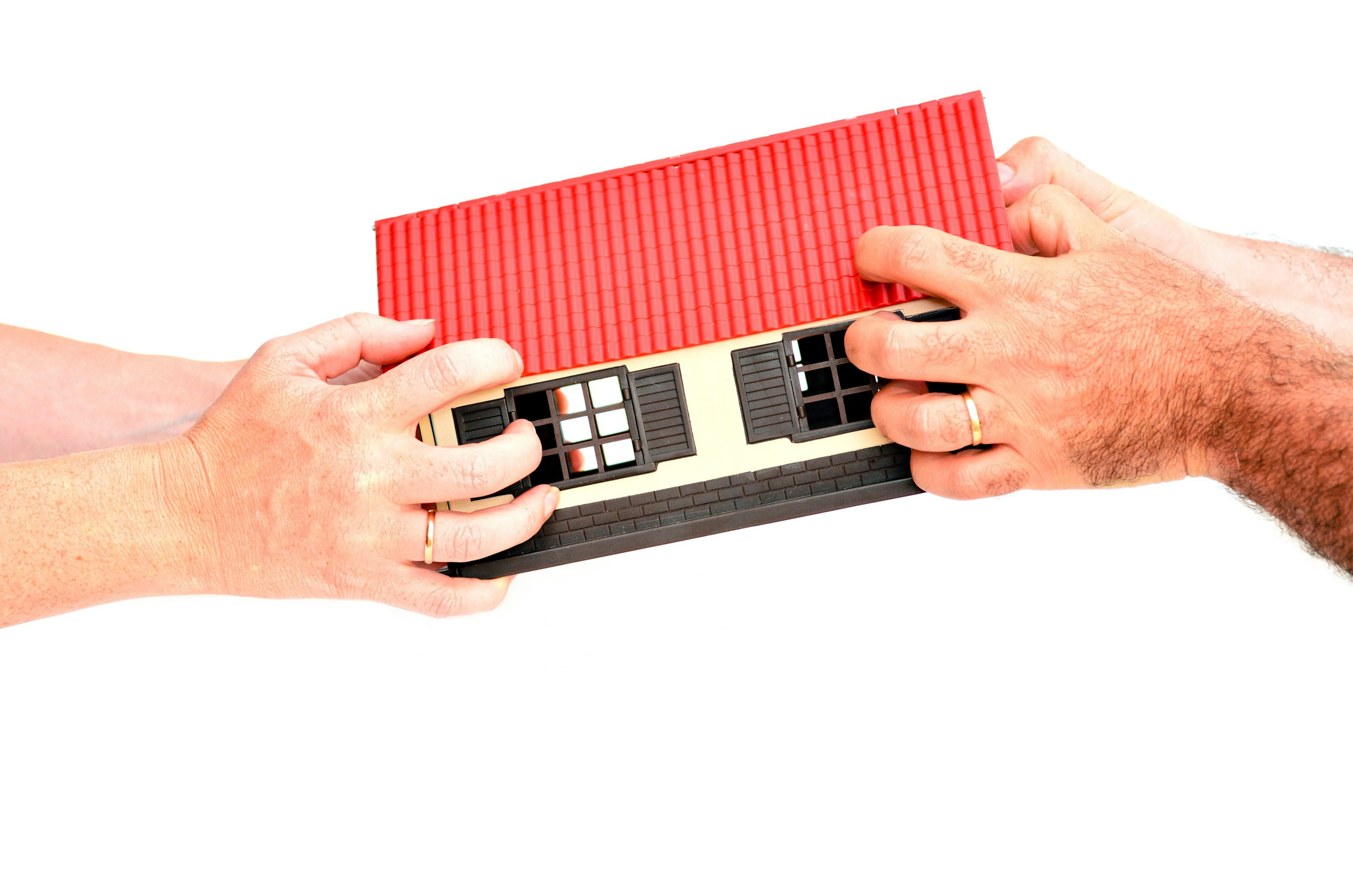 En mand og en kvinde hiver i hver sin ende af en model af et hus.