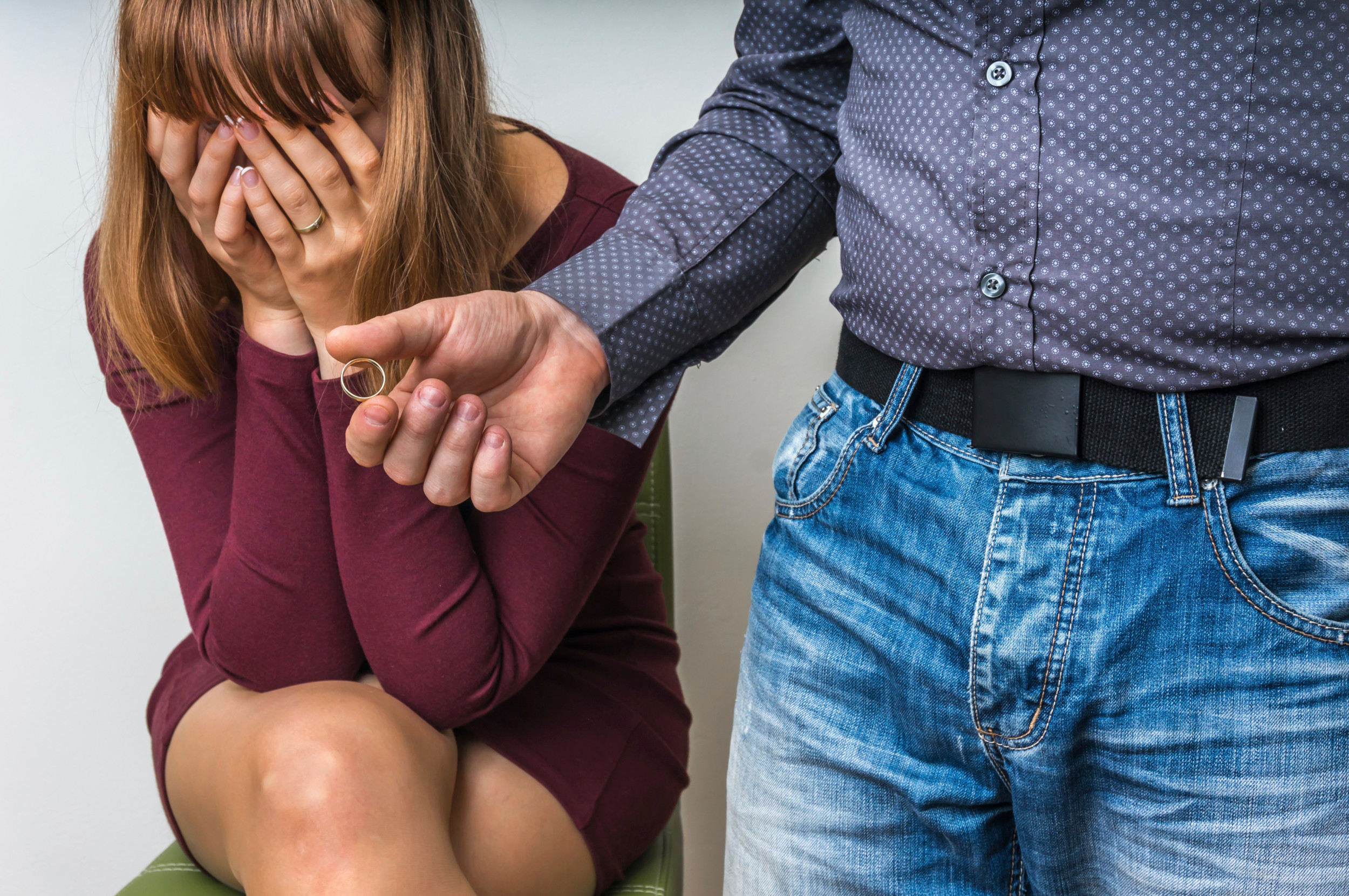 En mand rækker sin vielsesring frem mod sin kone, der sidder med hænderne for øjnene.