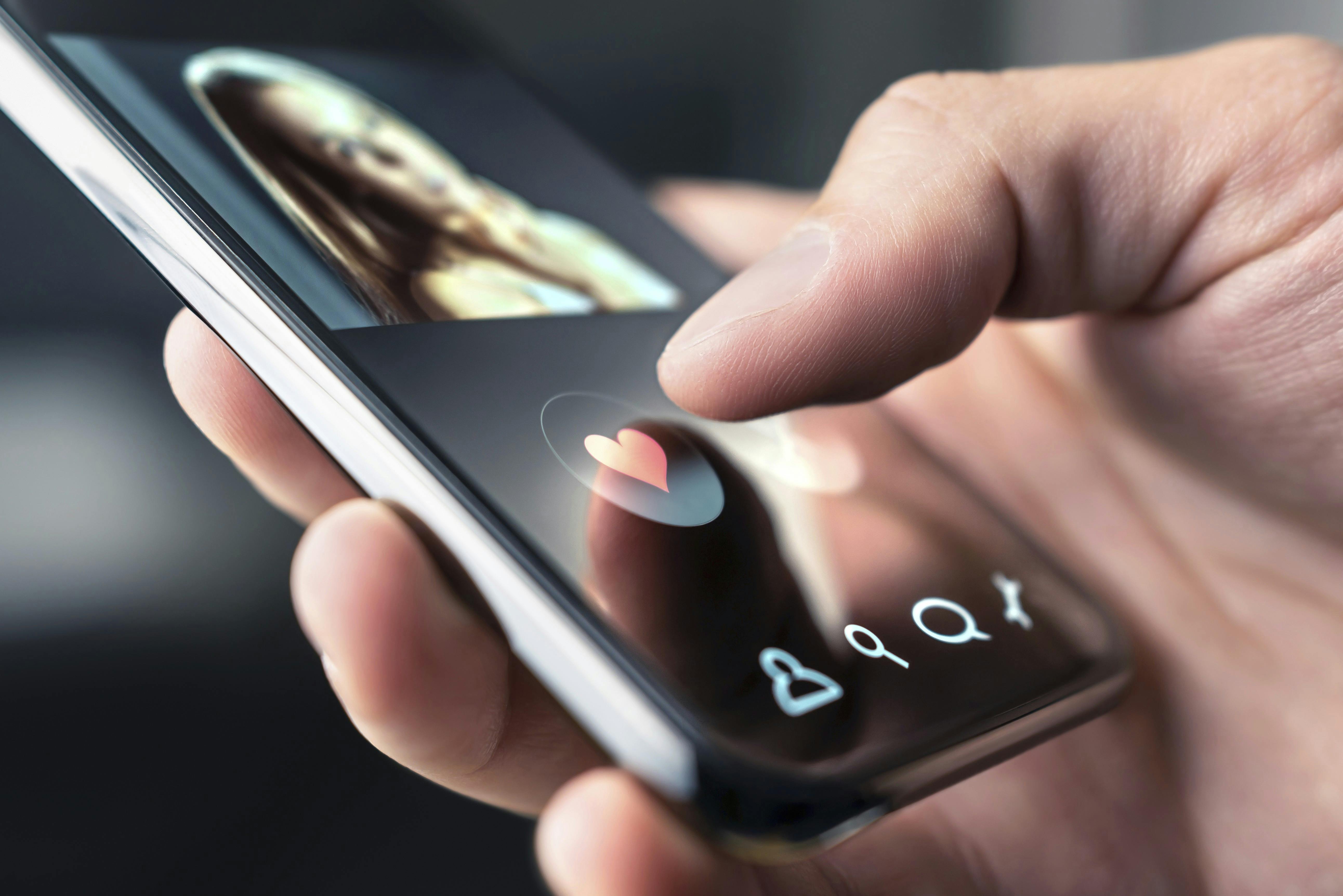 Hånd og telefon med dating-symbol.