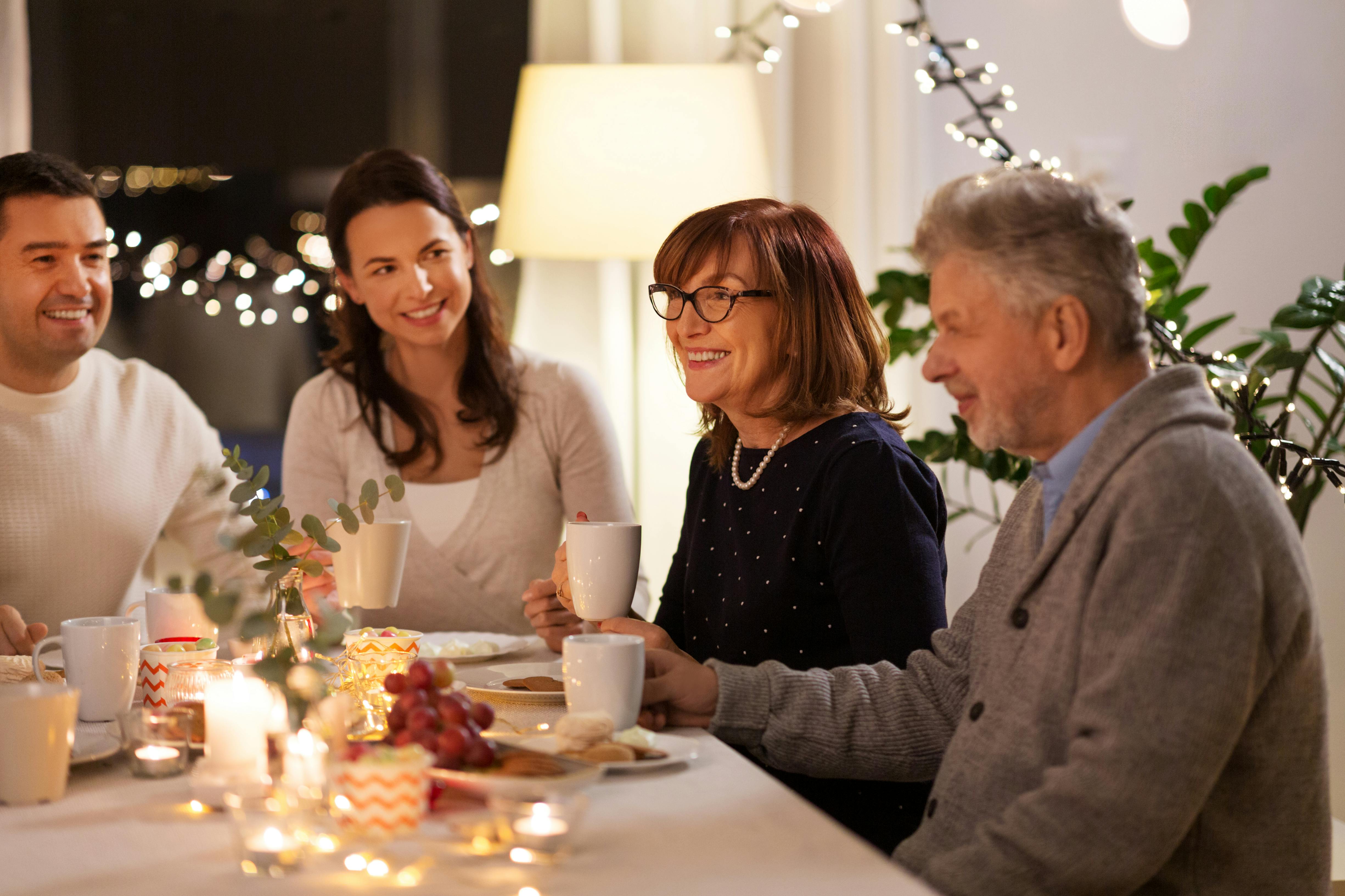 Familie samlet ved et festdækket bord, hvor de alle smiler lidt anstrengt.