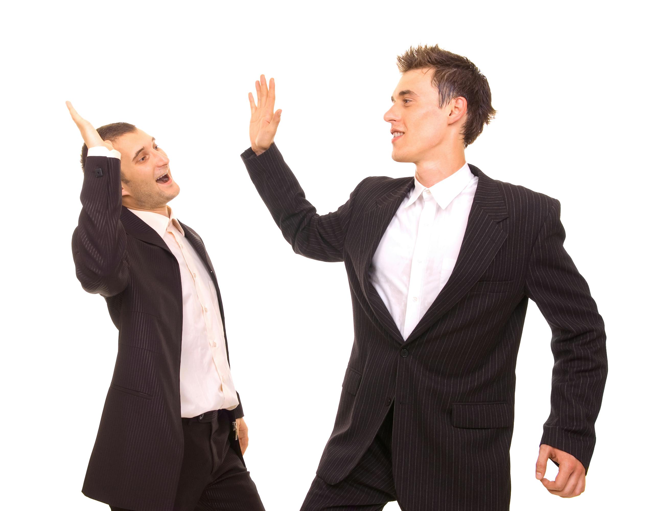 To unge mænd i jakkesæt giver hinanden high five.