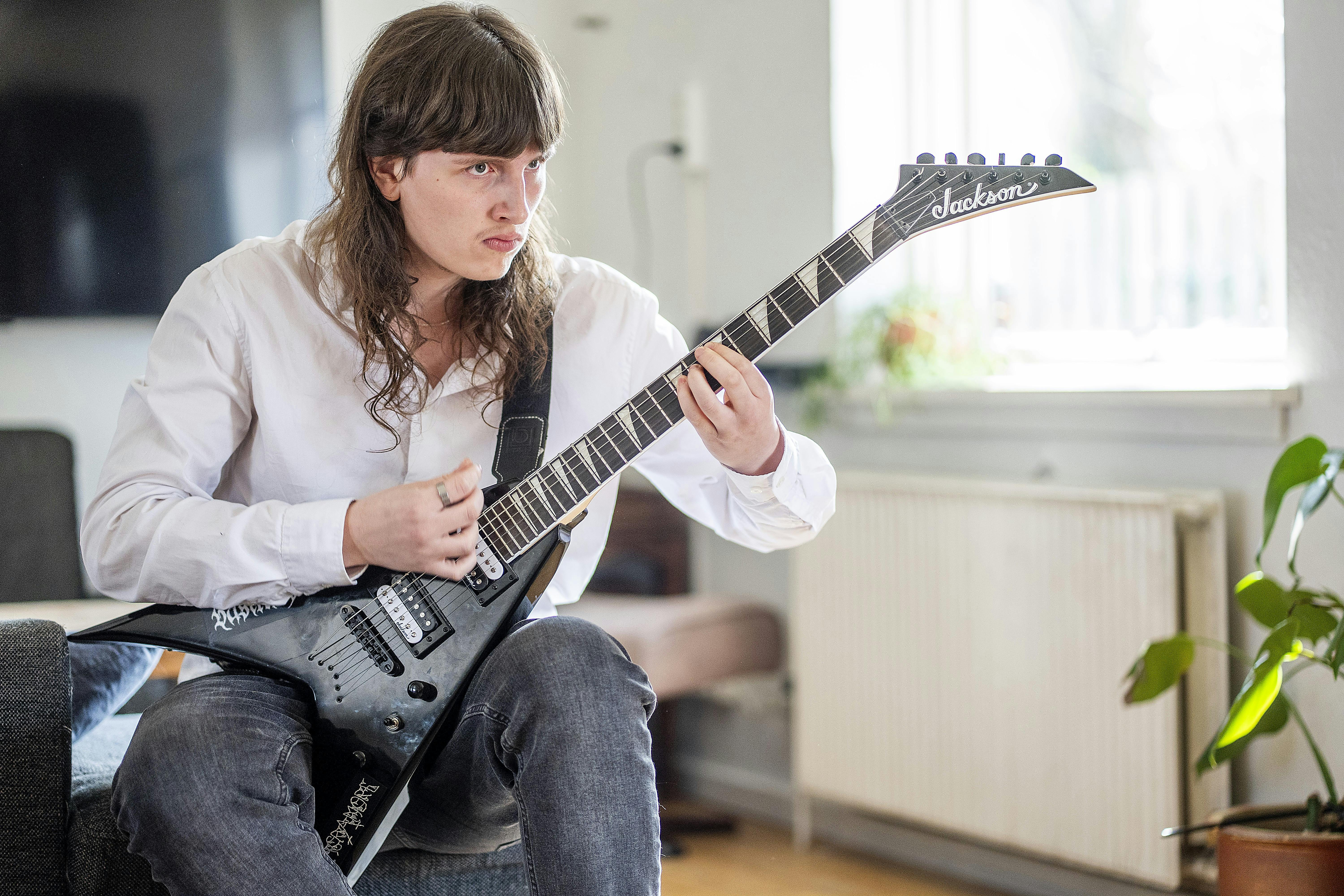 Alexander der sidder og spiller guitar. 