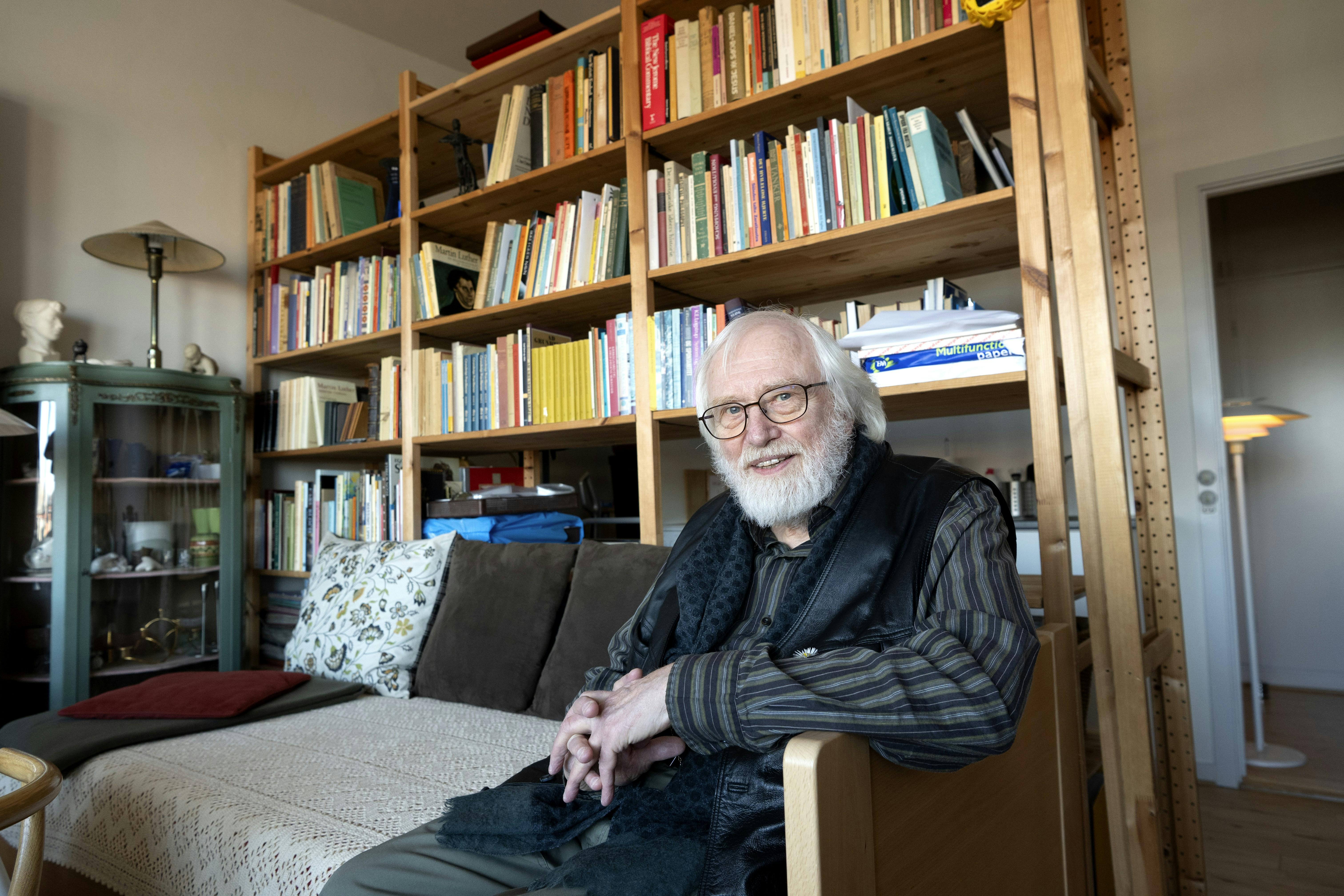 Bjørn der sidder i sin sofa. Der er en kæmpe bogreol i baggrunden. 