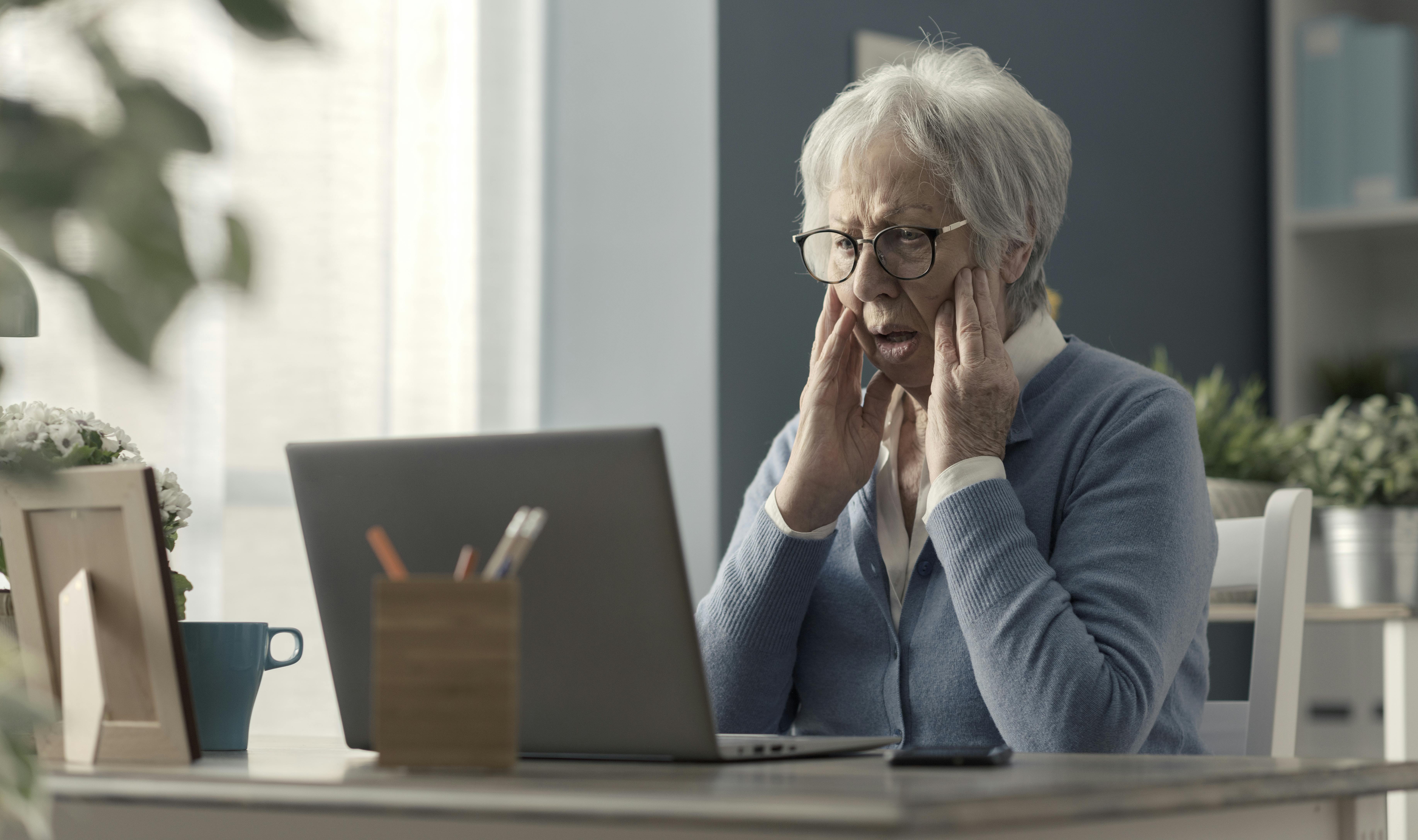 Ældre dame kigger chokeret på computerskørm
