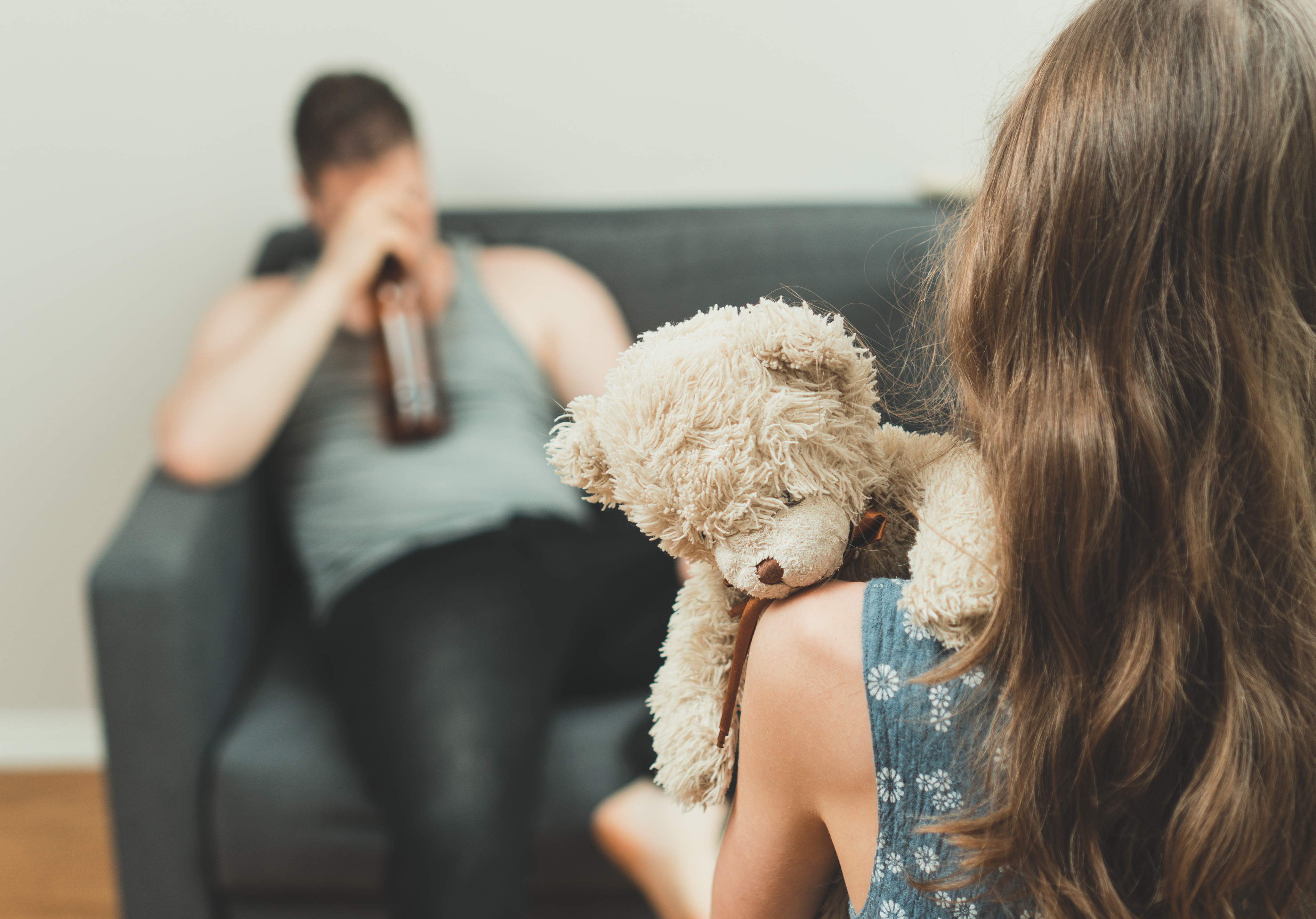 Lille pige kigger på sin far, der drikker alkohol