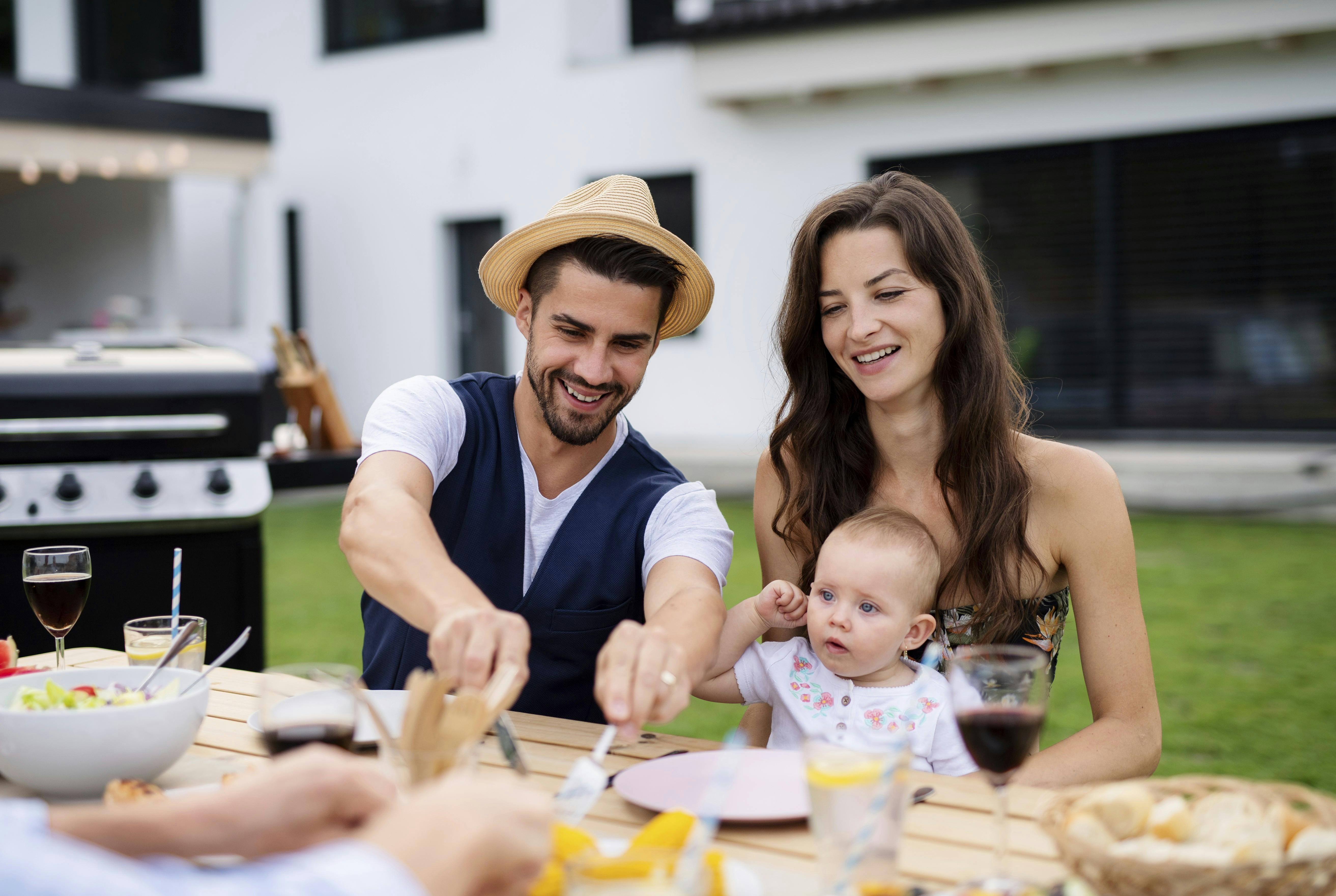 Flaskegas til grillen: Et ungt par, der sidder i deres have med deres baby