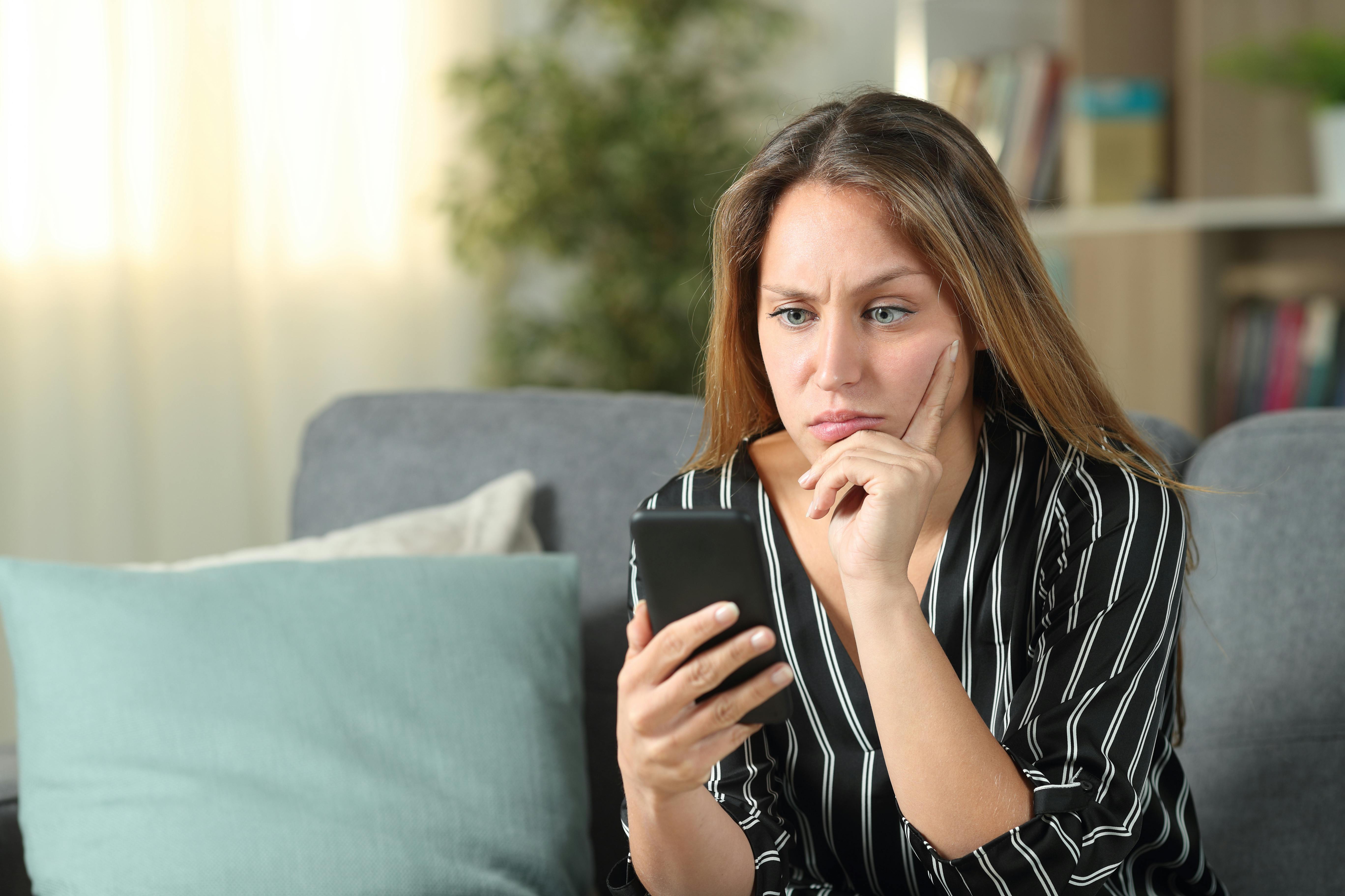 Kvinde ser opgivende på sin mobiltelefon.