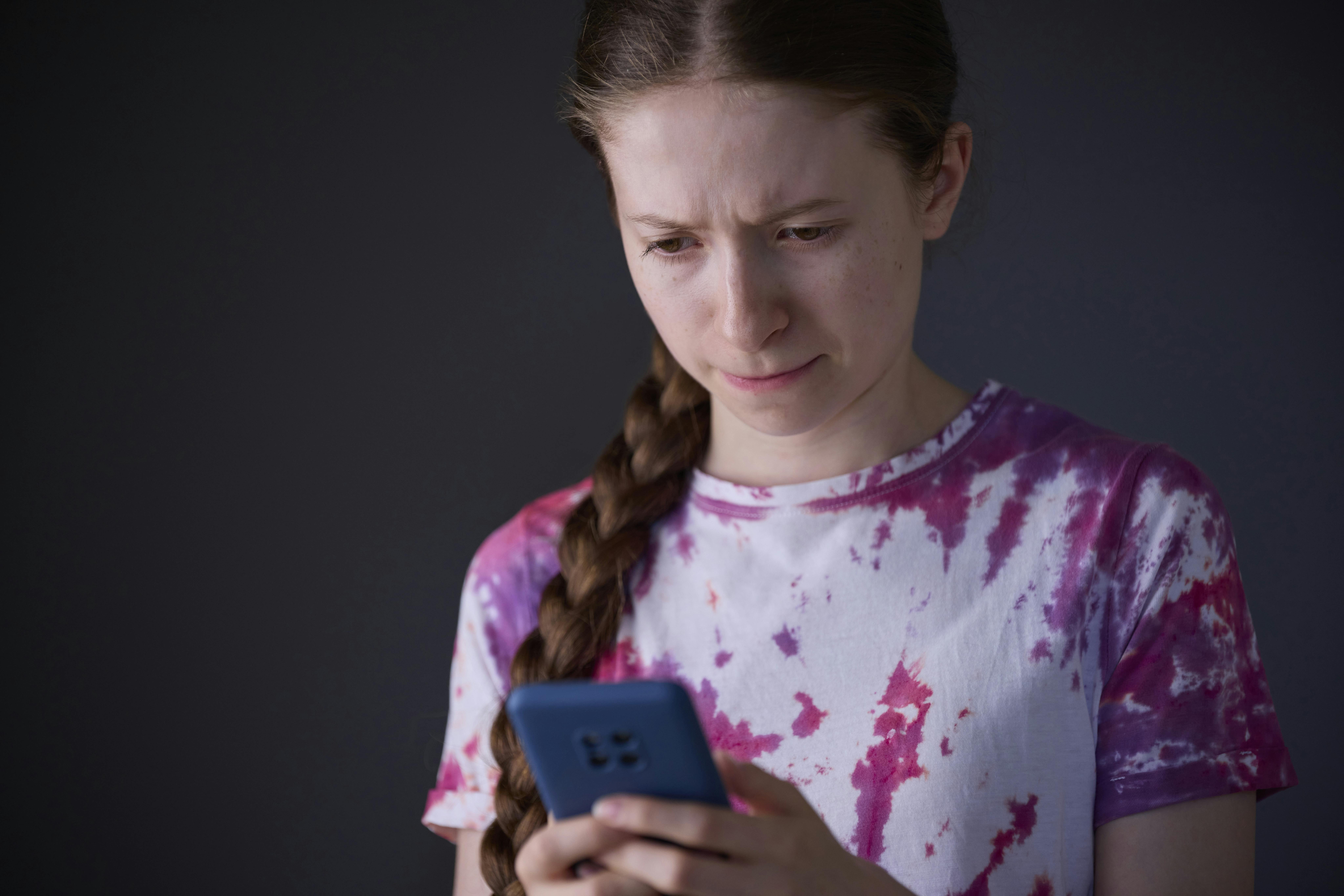 Ung pige kigger fortvivlet på mobiltelefon