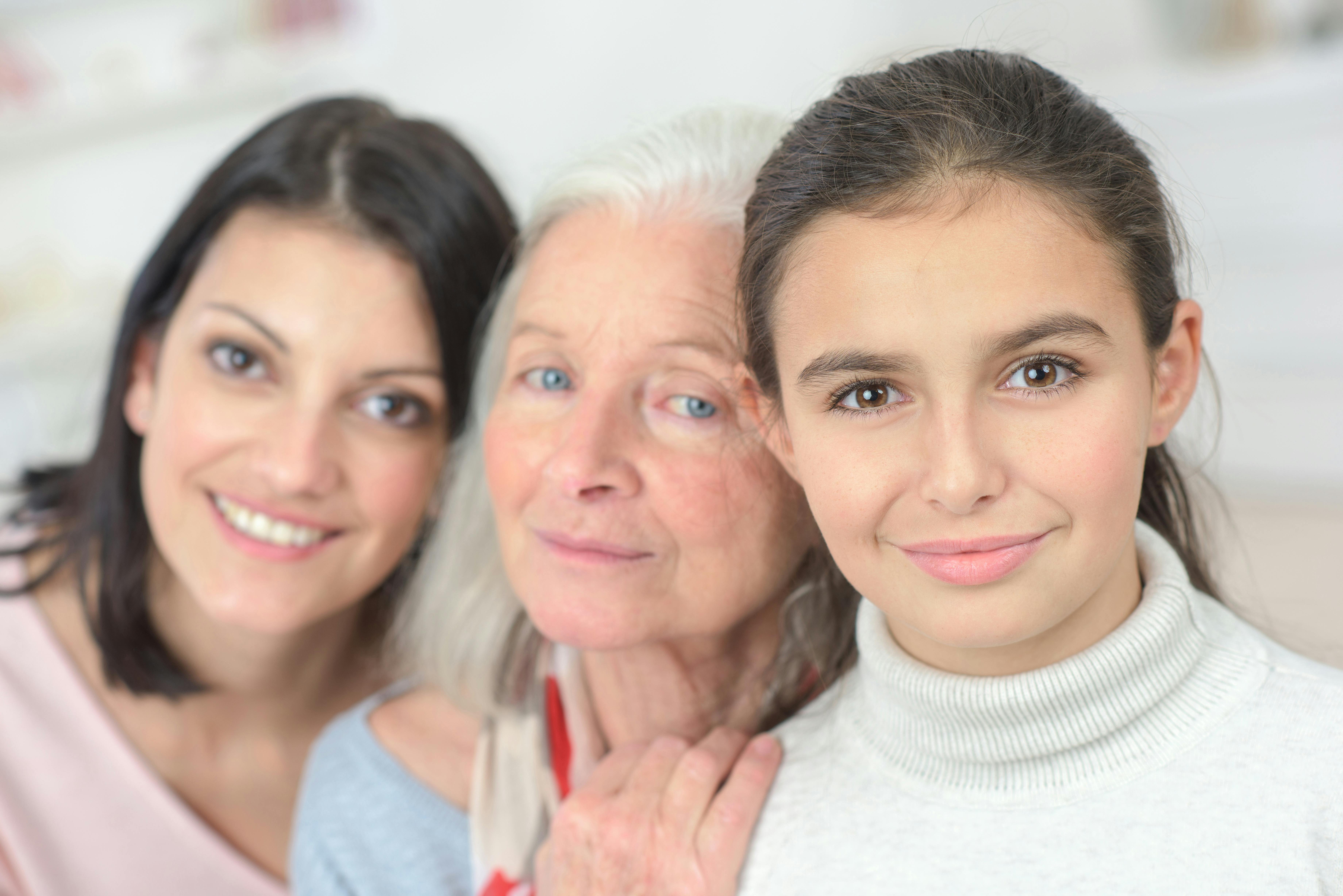 Tre kvinder, mor, mormor og datter ser smilende mod kameraet.