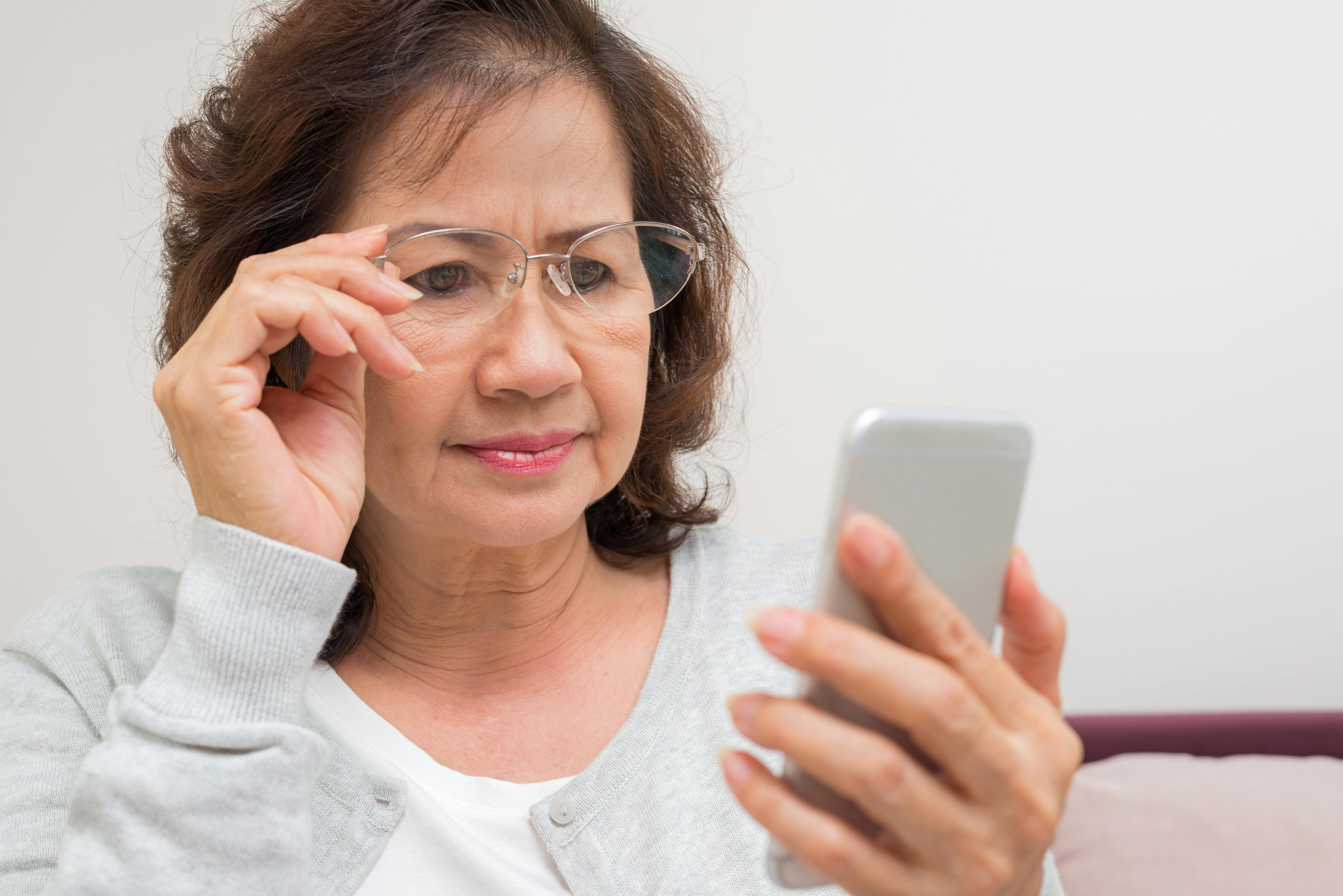 Midaldrende kvinde ser bekymret på sin mobiltelefon.