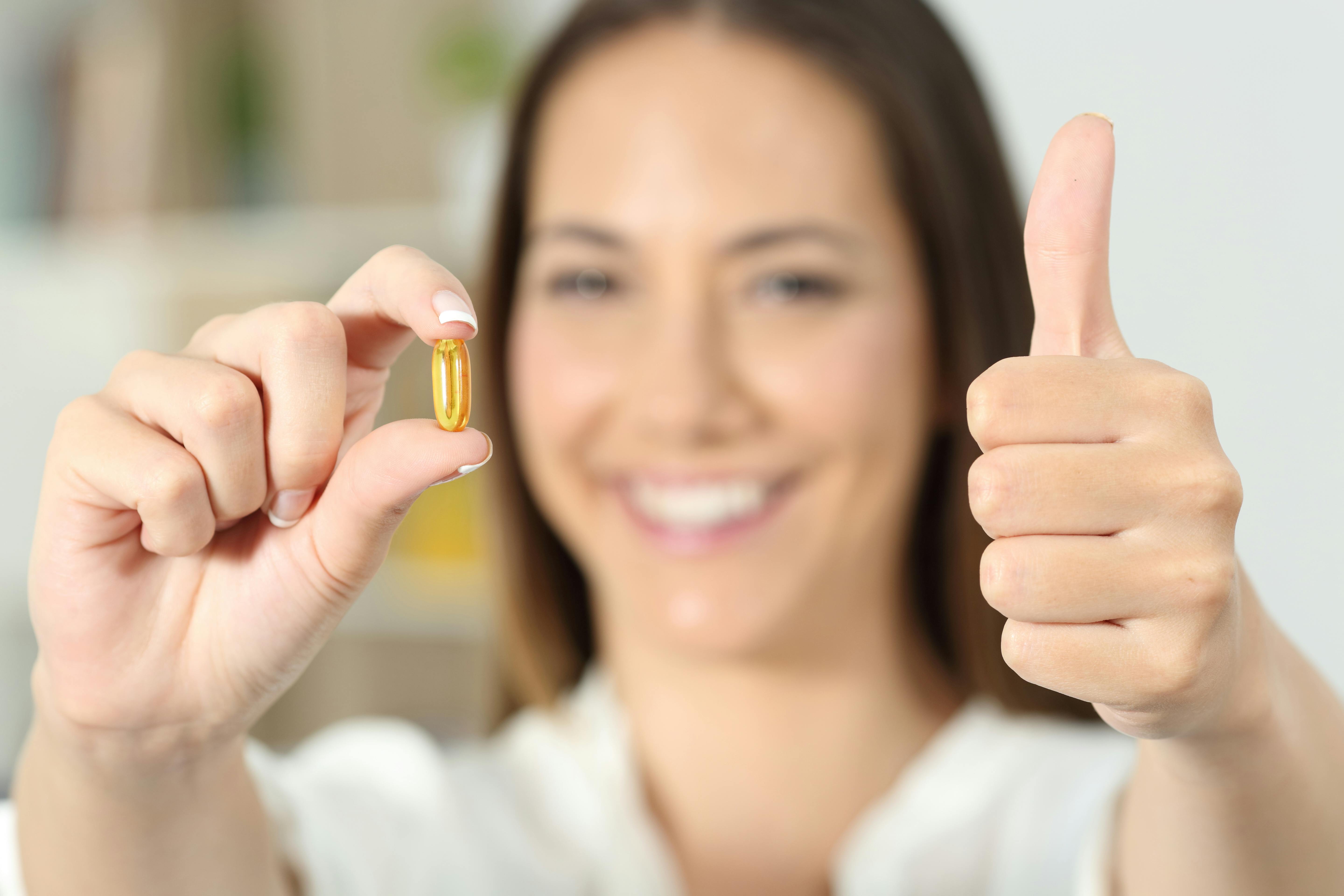 Glad kvinde med en C-vitaminpille i hånden