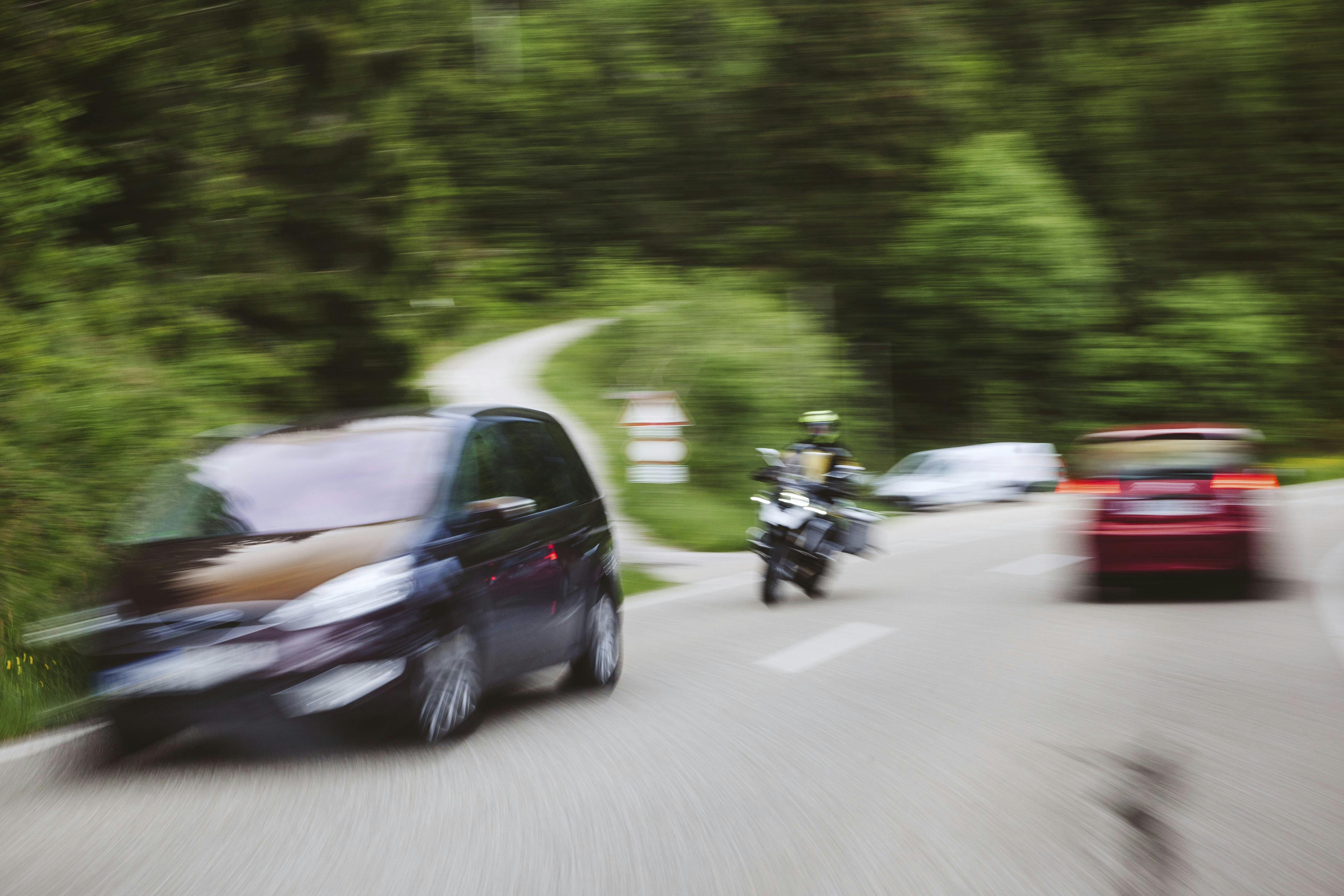Motoryckel og bil i fart på landevej