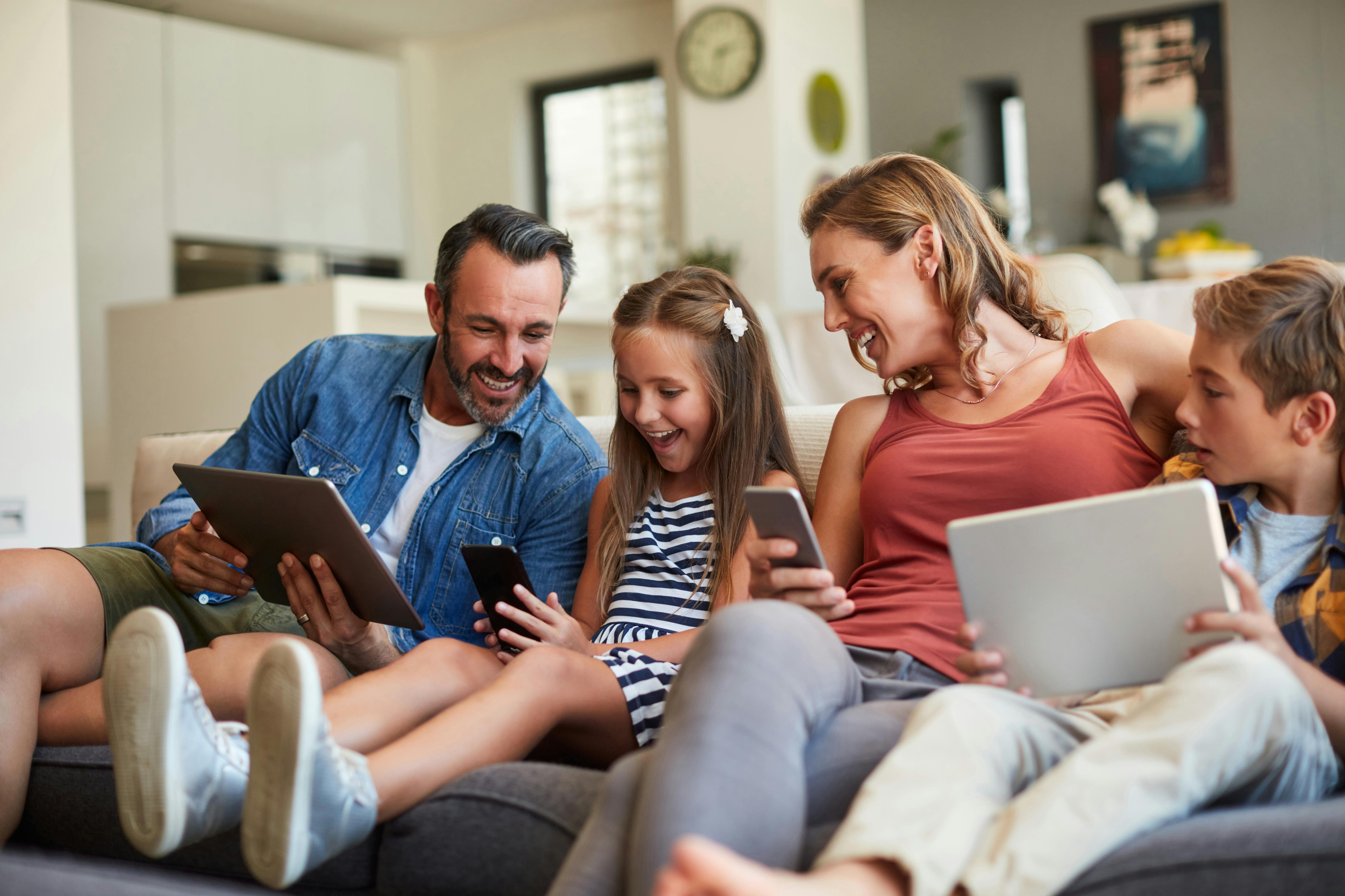 Familie samlet med computere og telefoner.