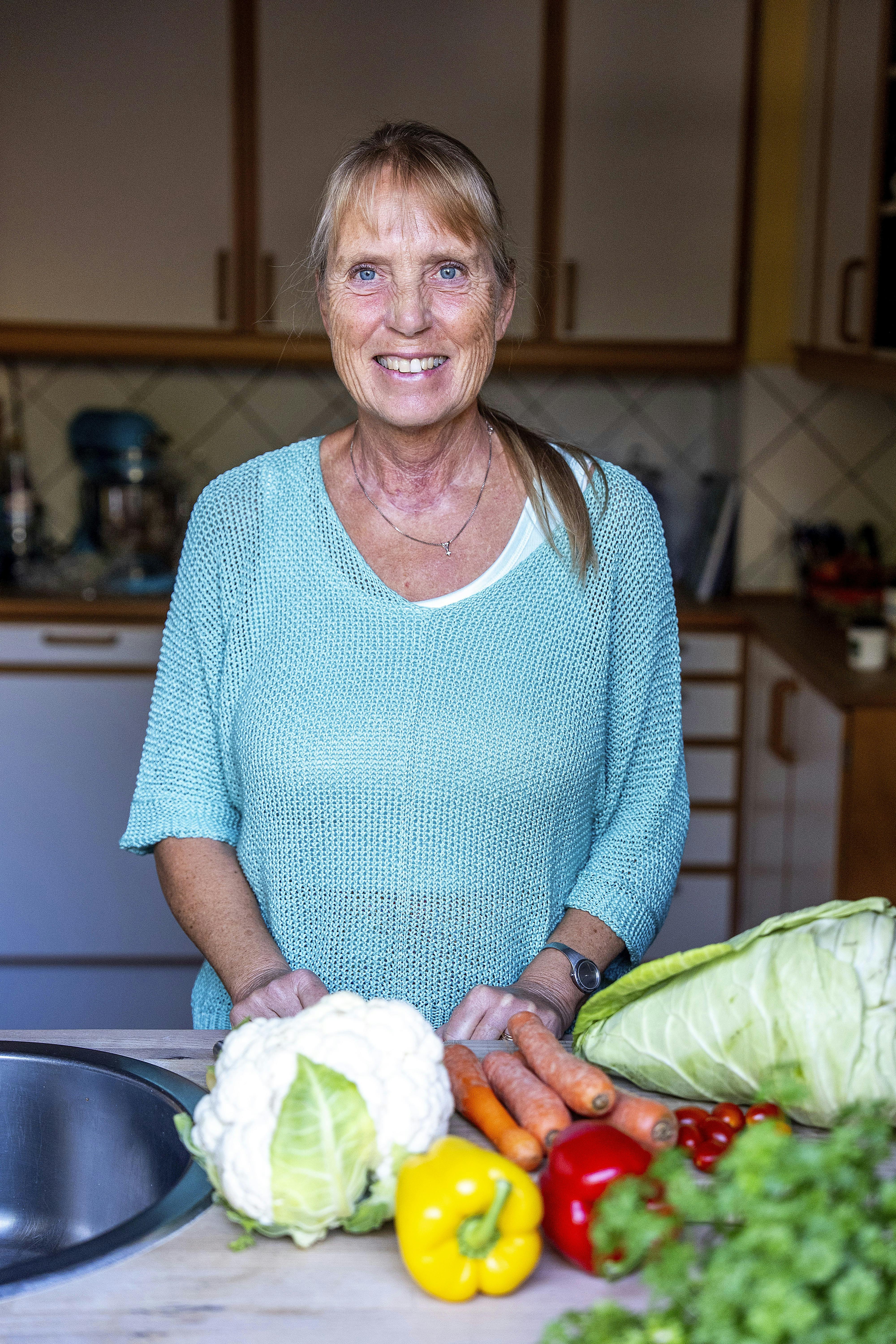 Britta Nielsen står i sit køkken med sunde grøntsager på køkkenbordet.