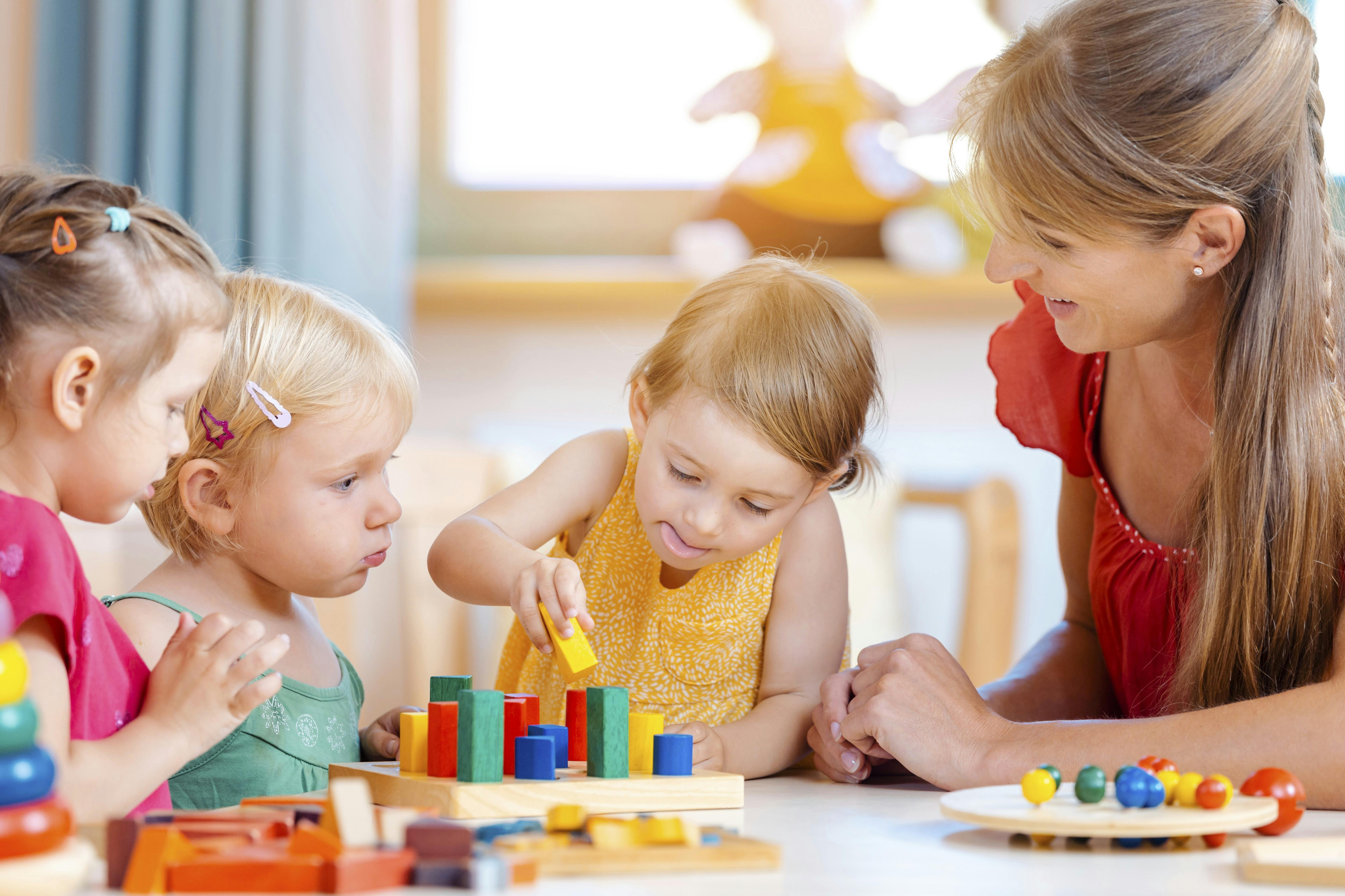 Modvægt til skærme: Børn leger foran en voksen kvinde.