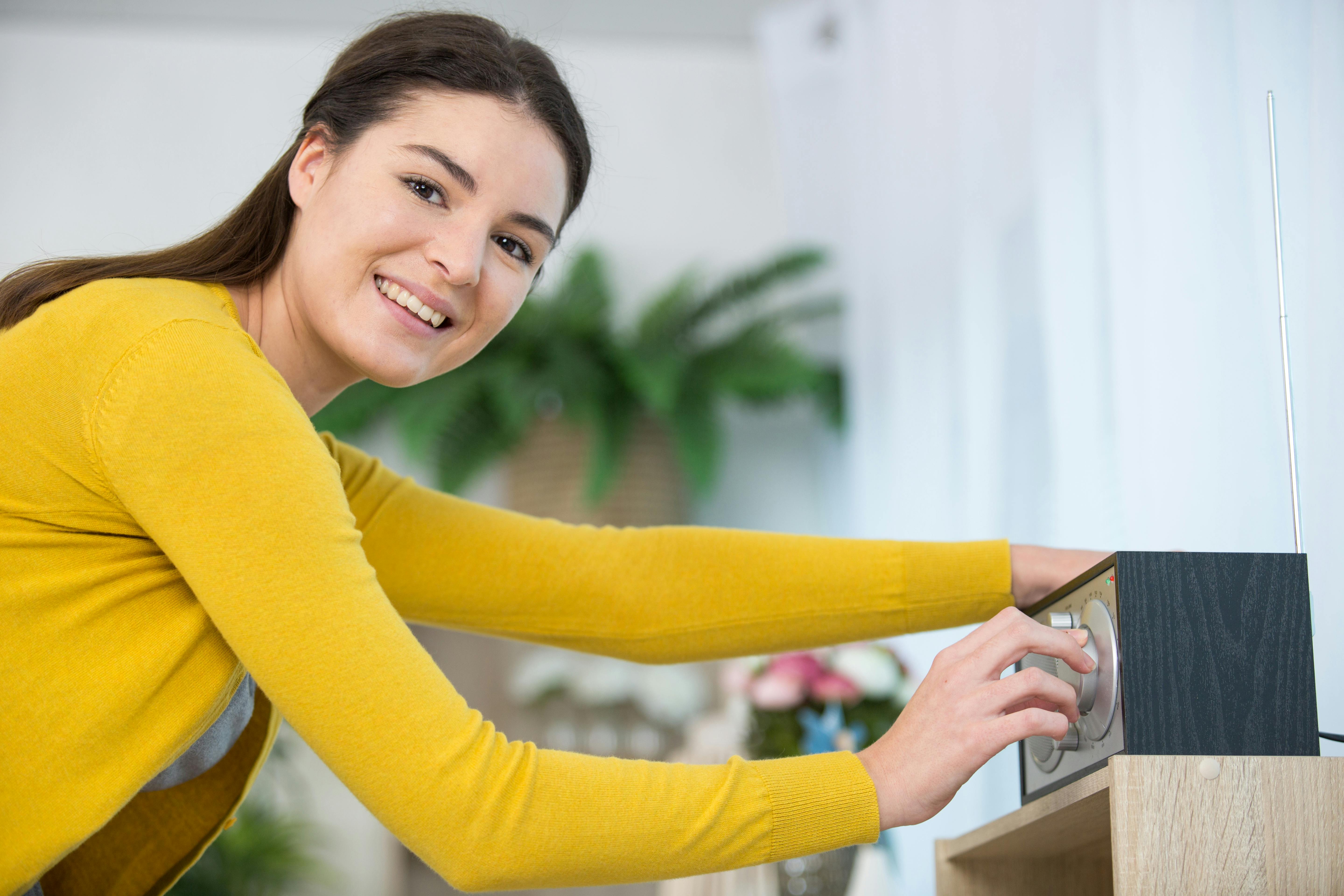 Rengøring af beskidt DAB-radio: Kvinde står ved radio