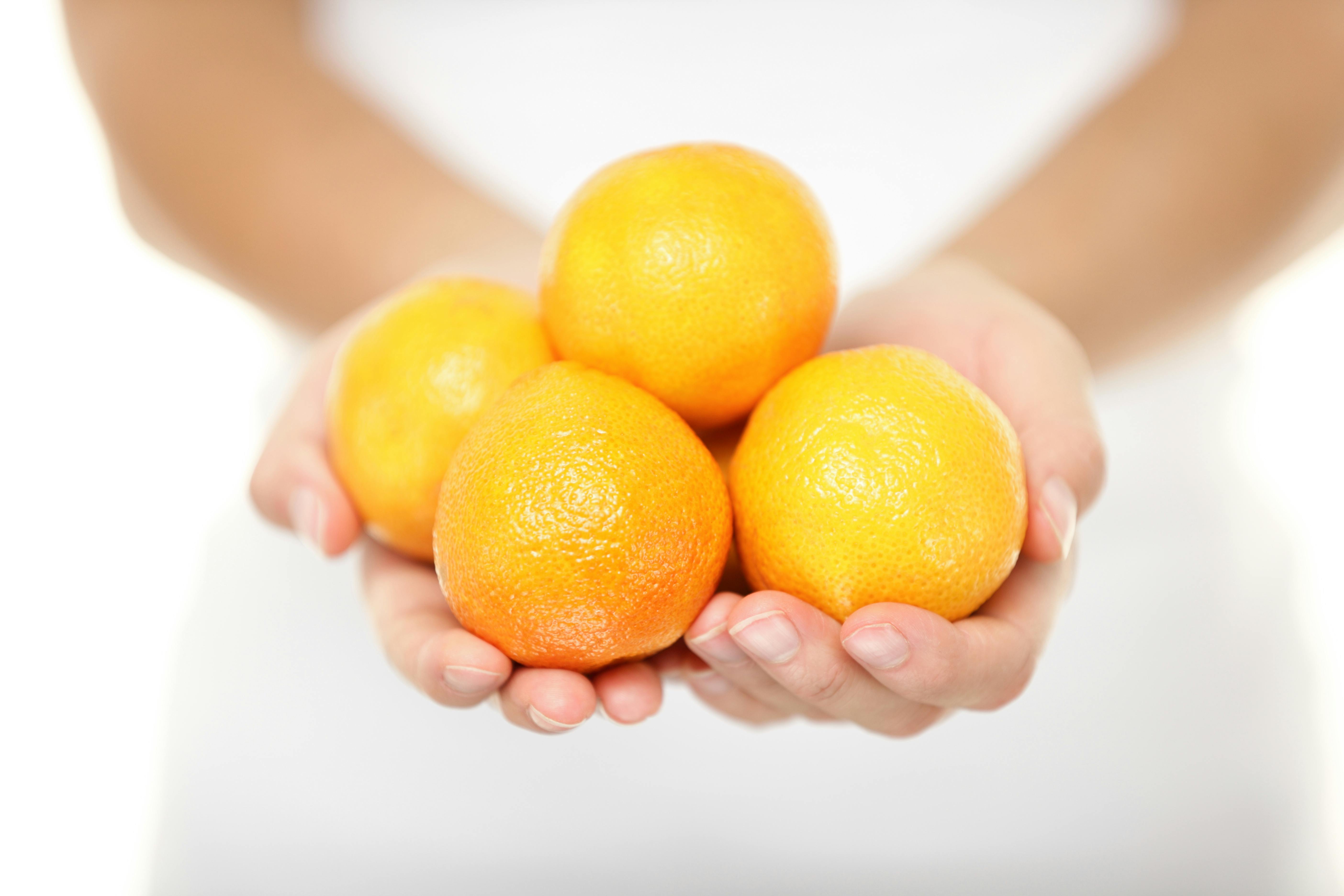 Klementiner: En kvinde holder flere klementiner i sine fremstrakte hænder