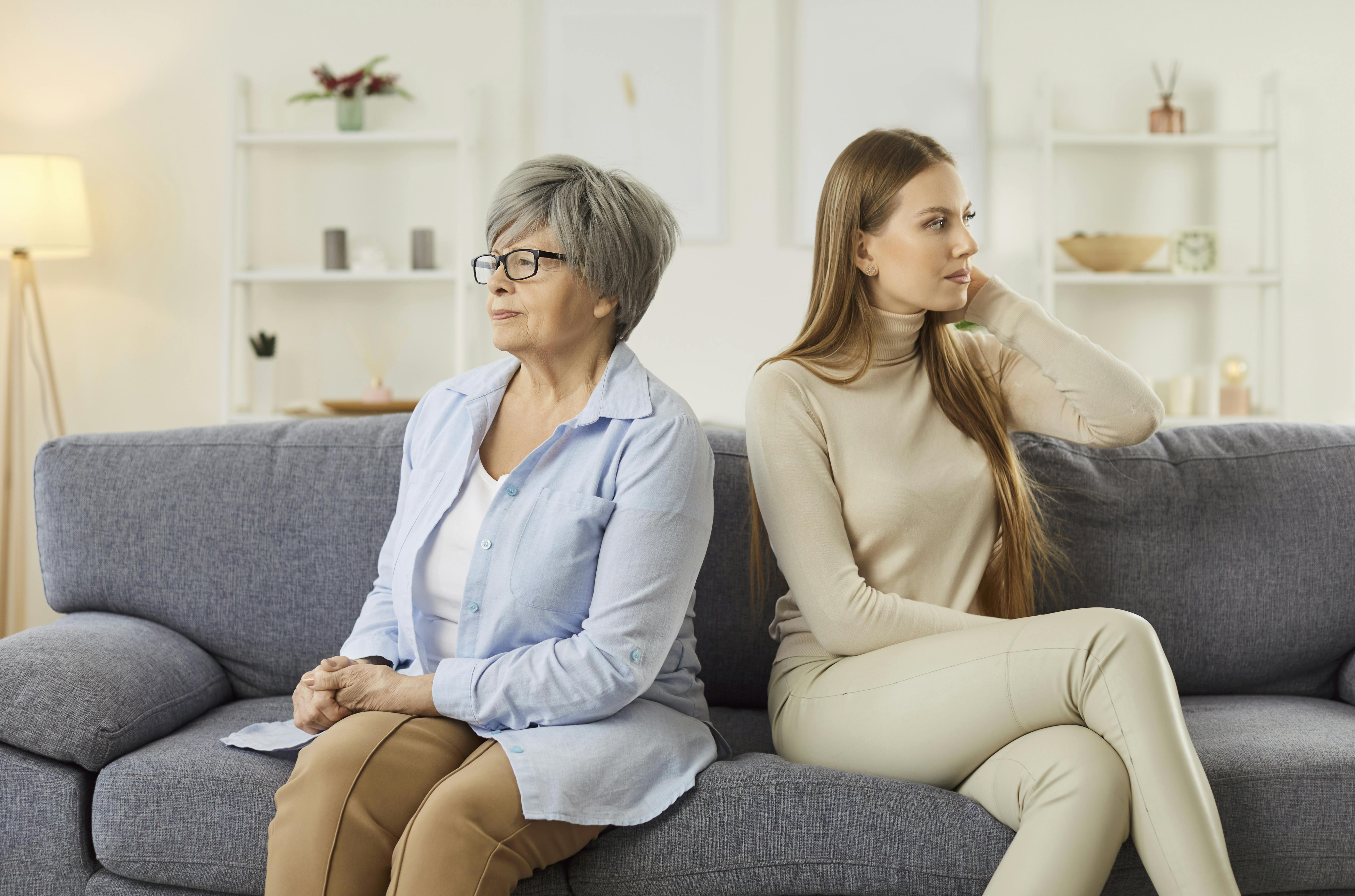 Børn: Mor og voksen datter sidder i en sofa med ryggen vredt vendt mod hinanden. 