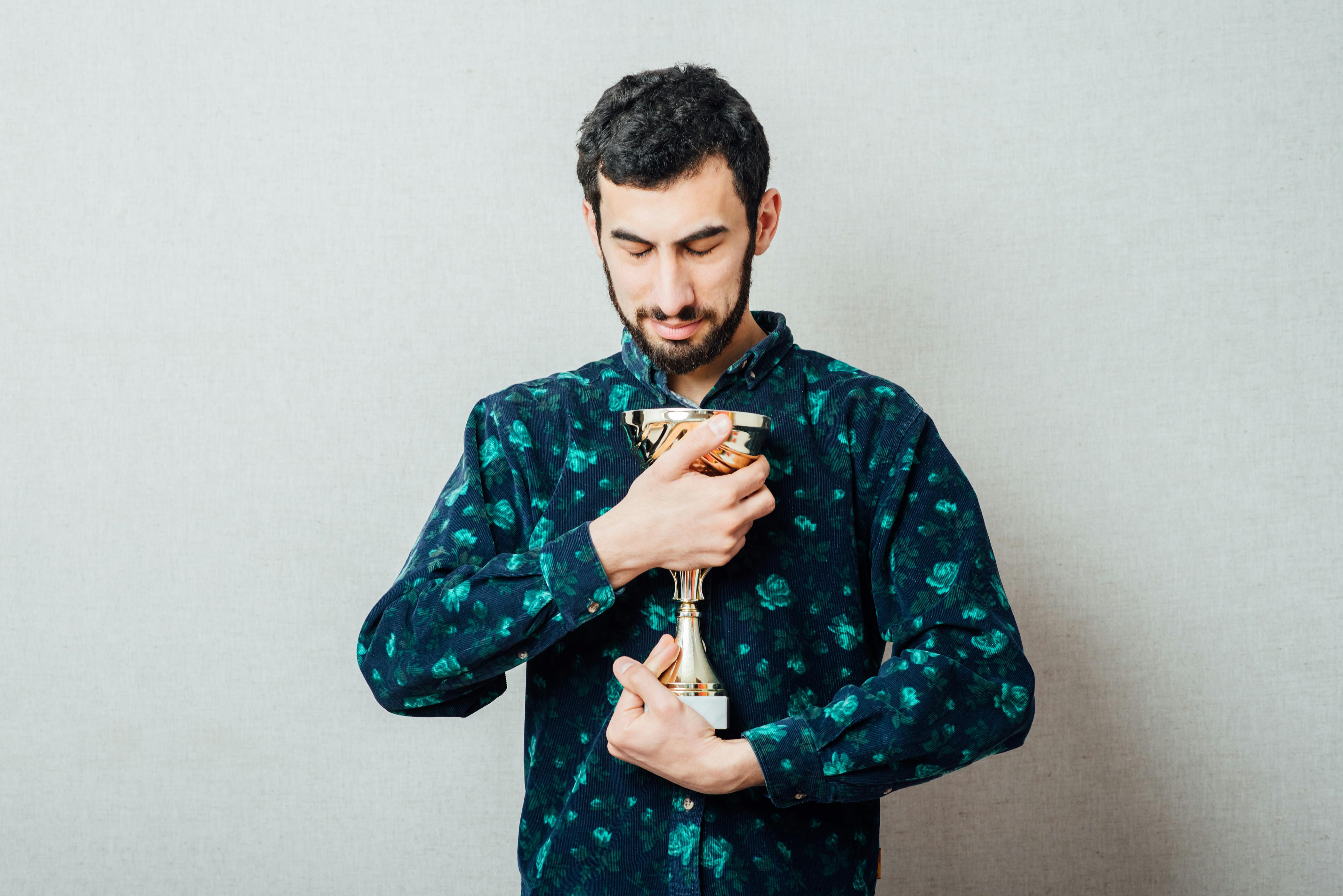 Fodboldpokalen er blevet kulsort. Mand holder en pokal.