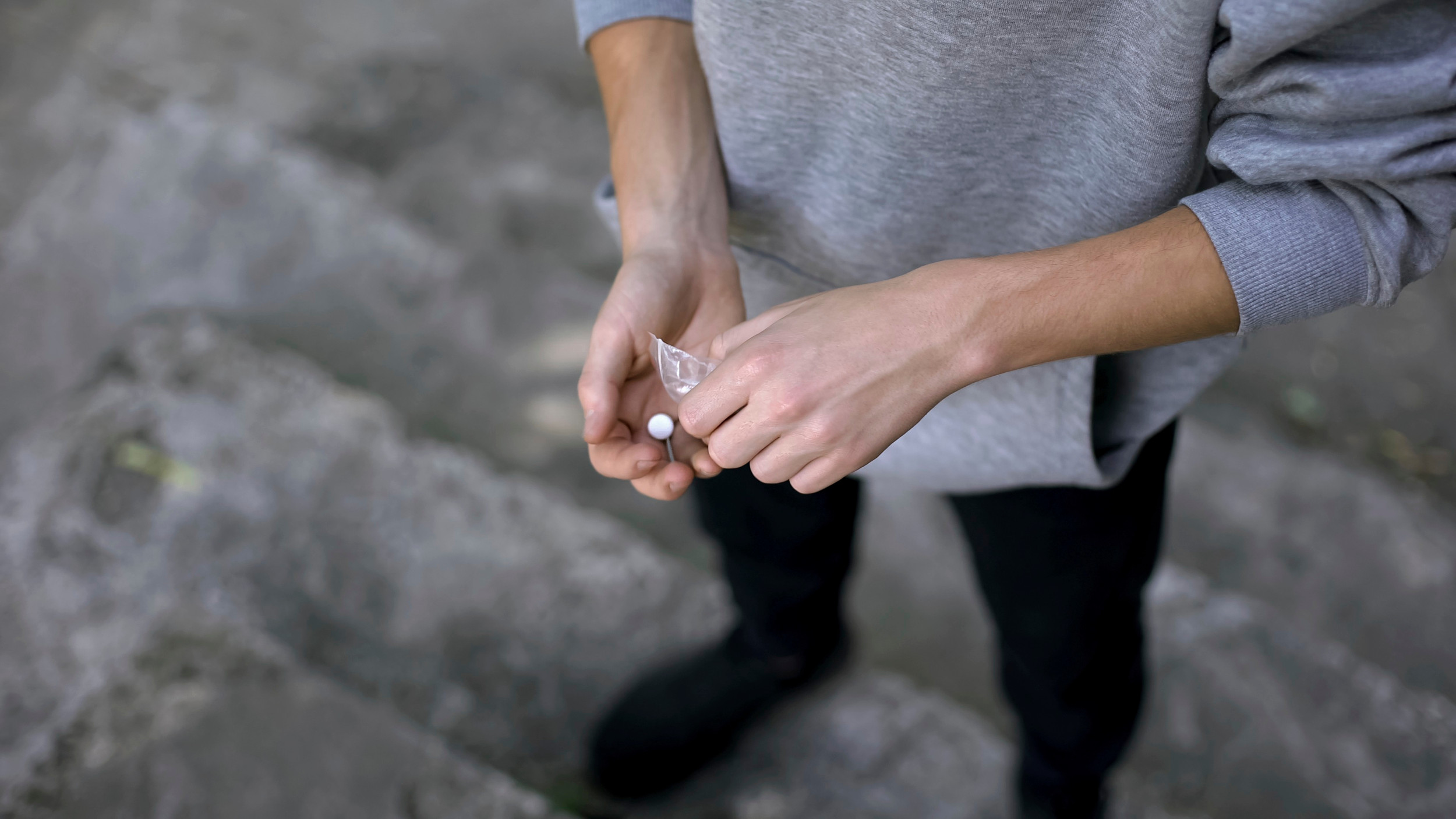 En ung mand står og hælder en pille ud af en lille pose.