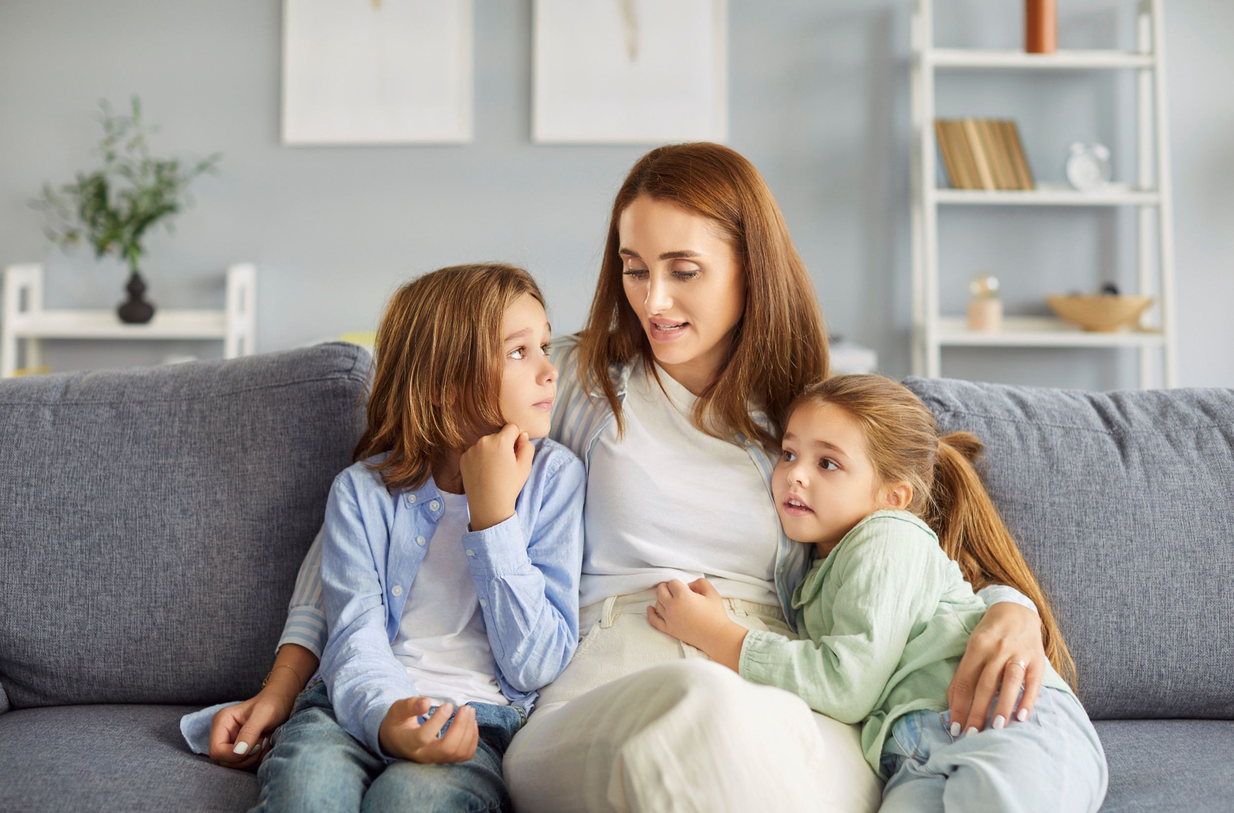 Skilsmissemor nægter at udlevere børnene til deres far: En mor sidder i sofaen og holder om sine to døtre.