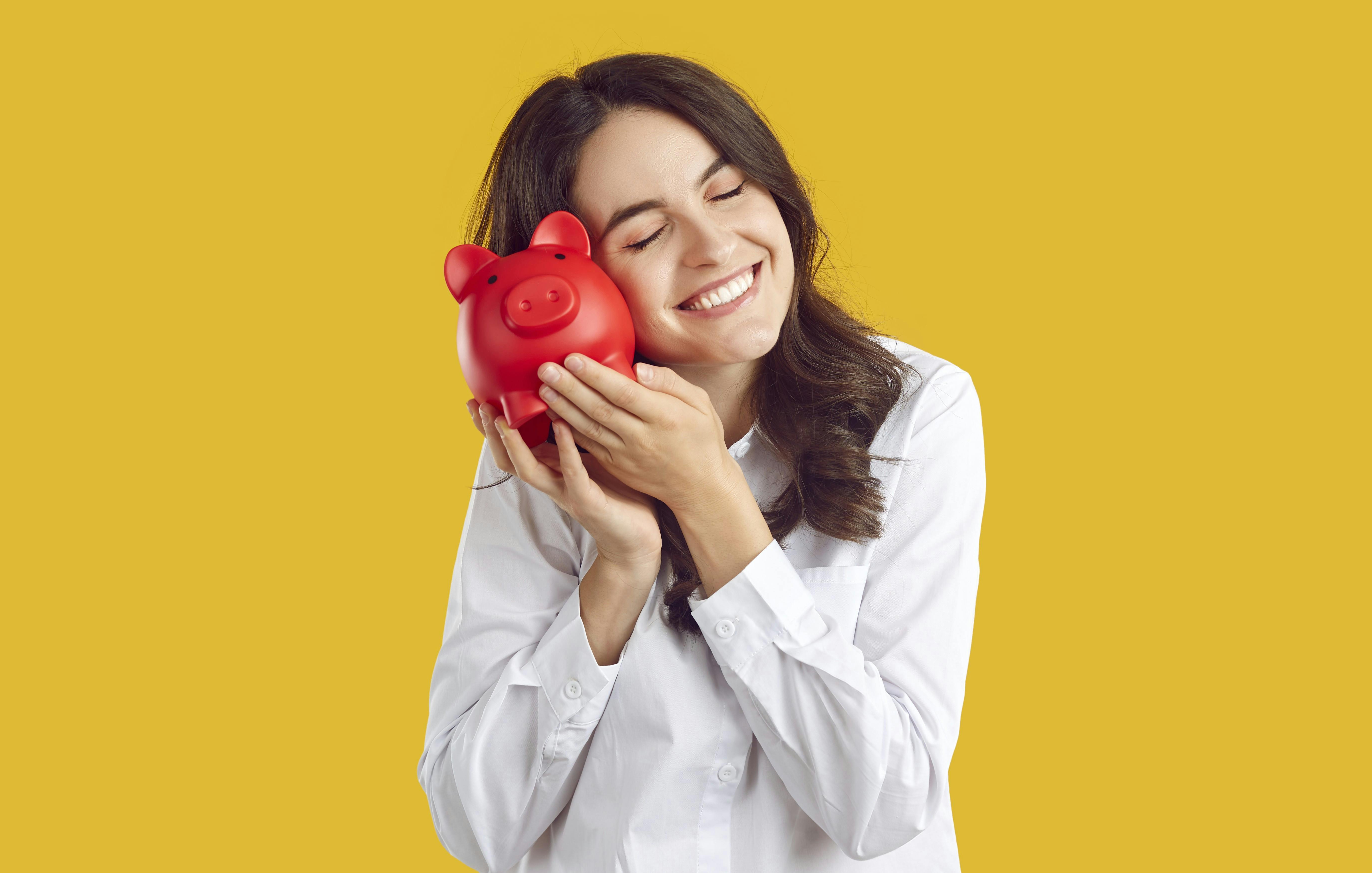 Sådan sparer du op til dine drømme: Glad kvinde krammer en sparegris