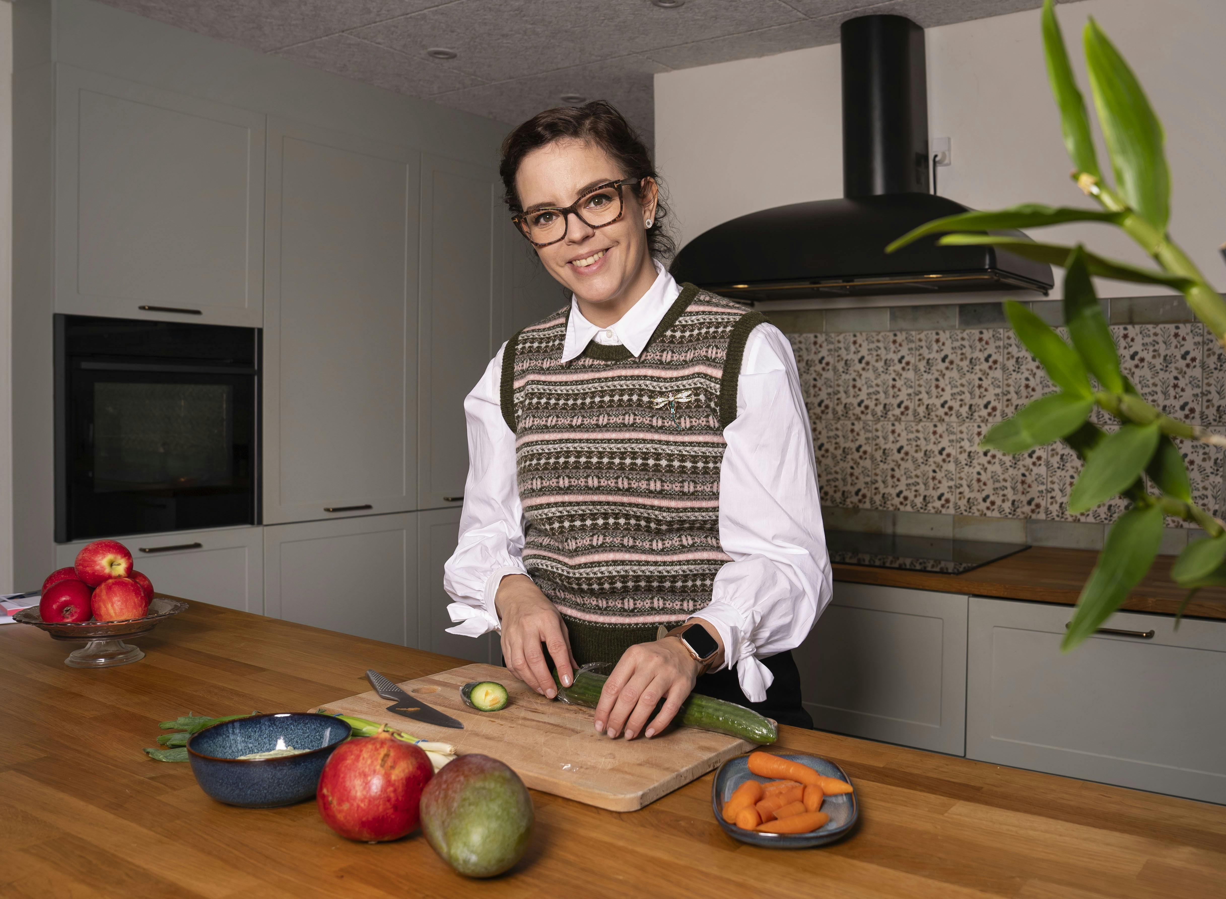 Tanja Madsen i sit køkken igang med at skære grøntsager til en sund salat.