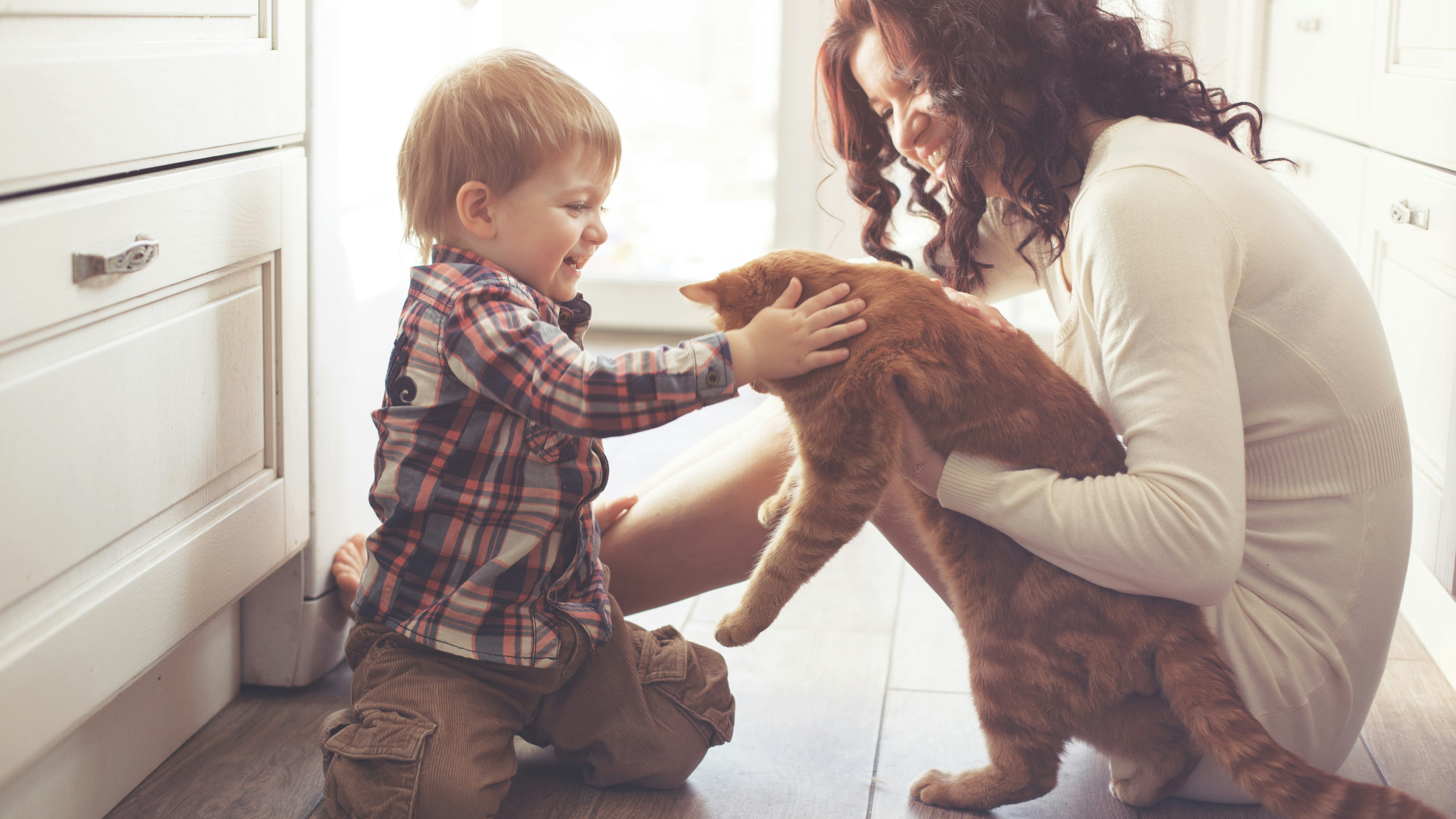 En kvinde og et barn sidder på gulvet med en kat