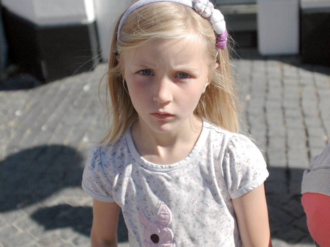 Pige på syv år ser trist ud mod kameraet