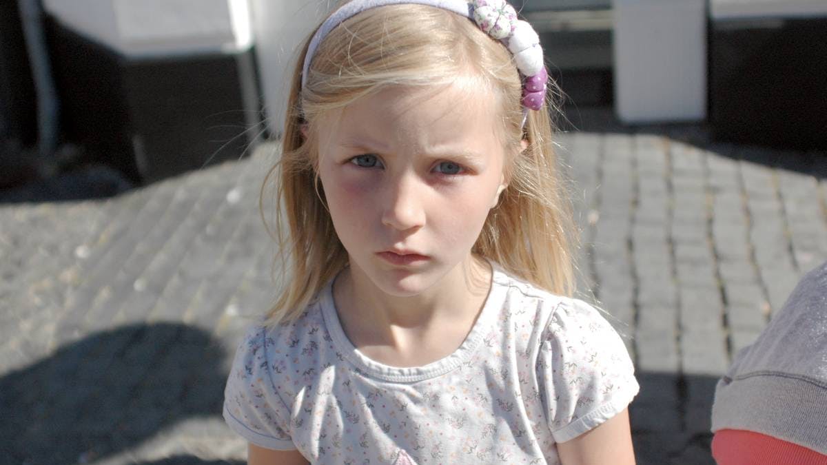 Pige på syv år ser trist ud mod kameraet