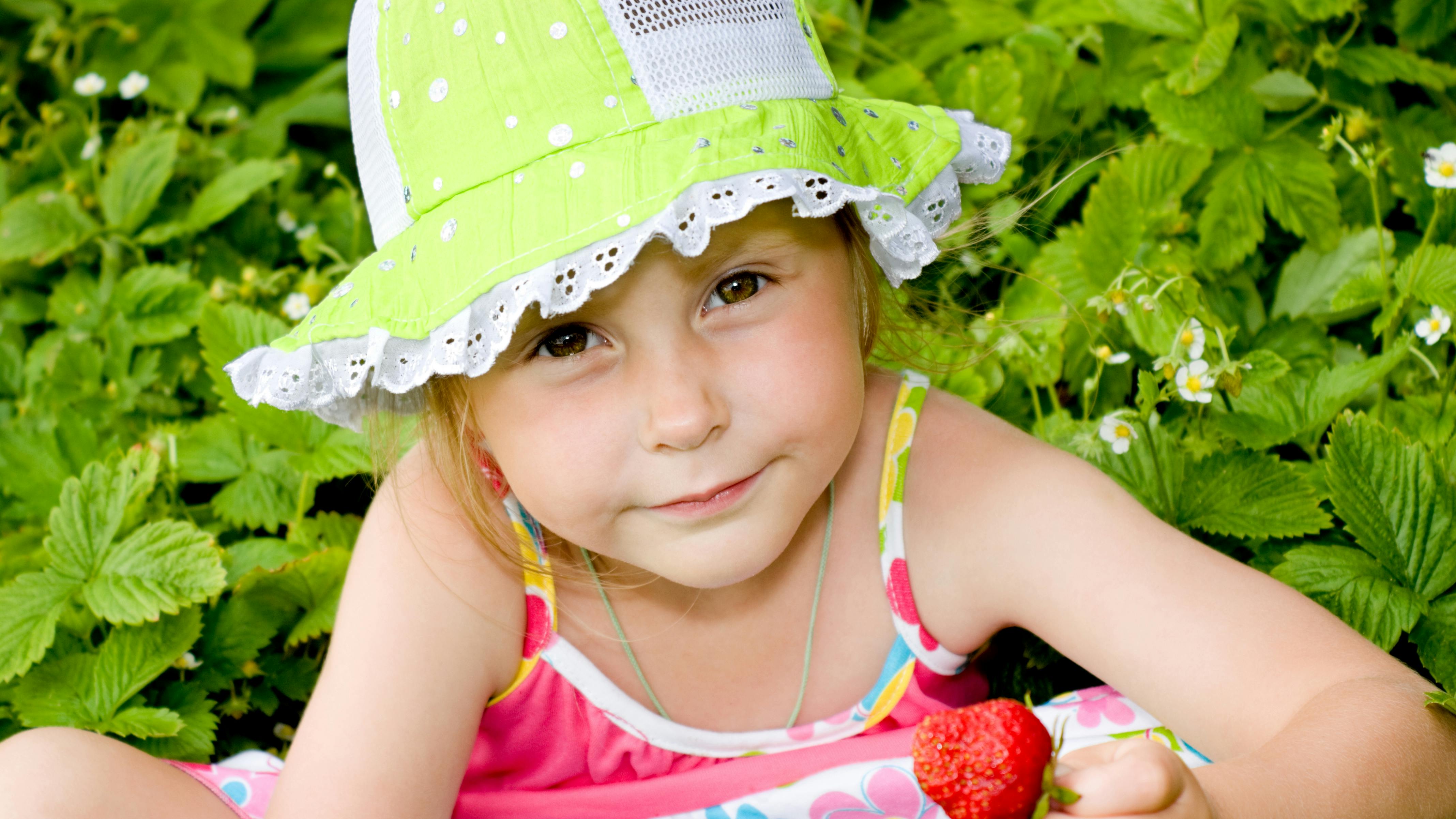 Et barn spiser plukker jordbær i haven 